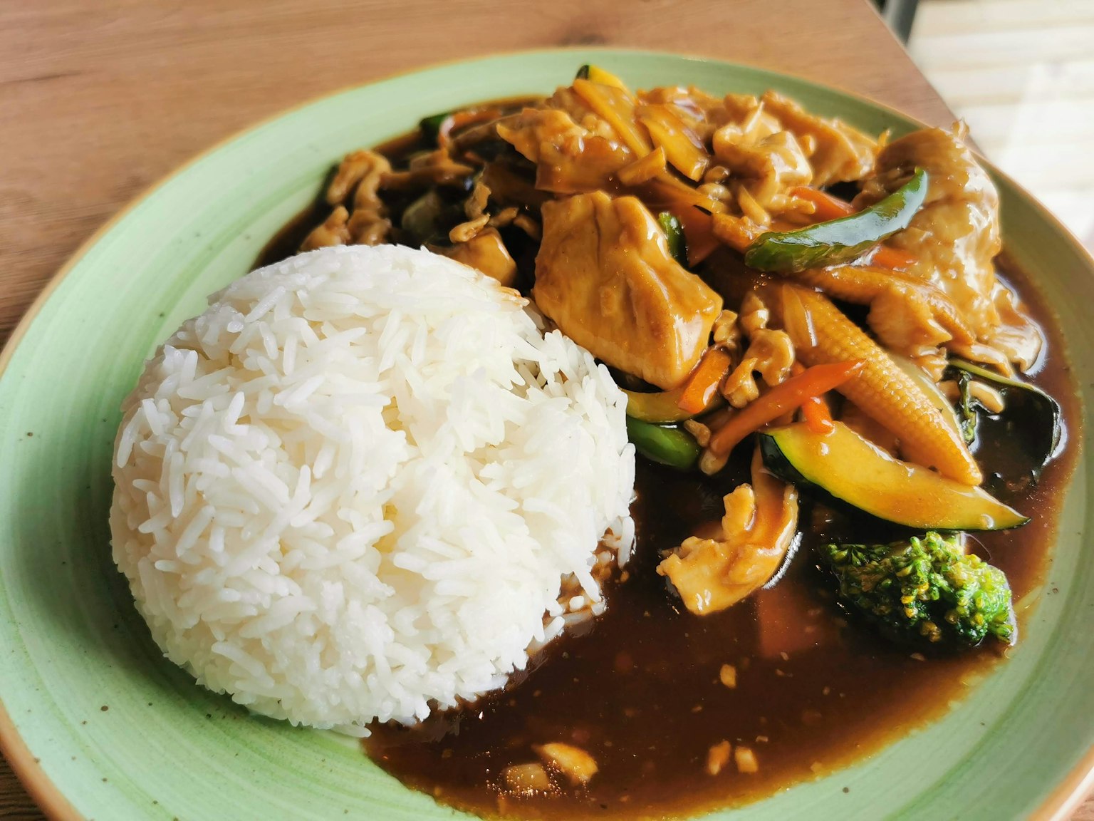 Piring nasi putih disajikan dengan ayam dan sayuran campur dalam saus coklat