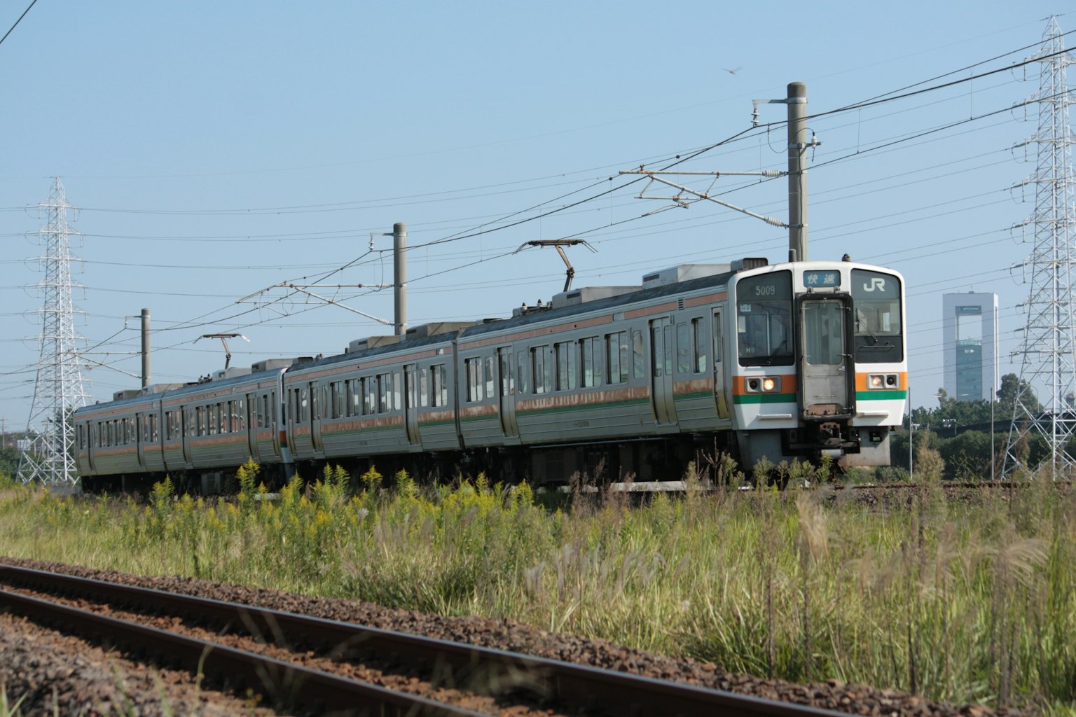 Vista lateral de un tren japonés circulando por praderas