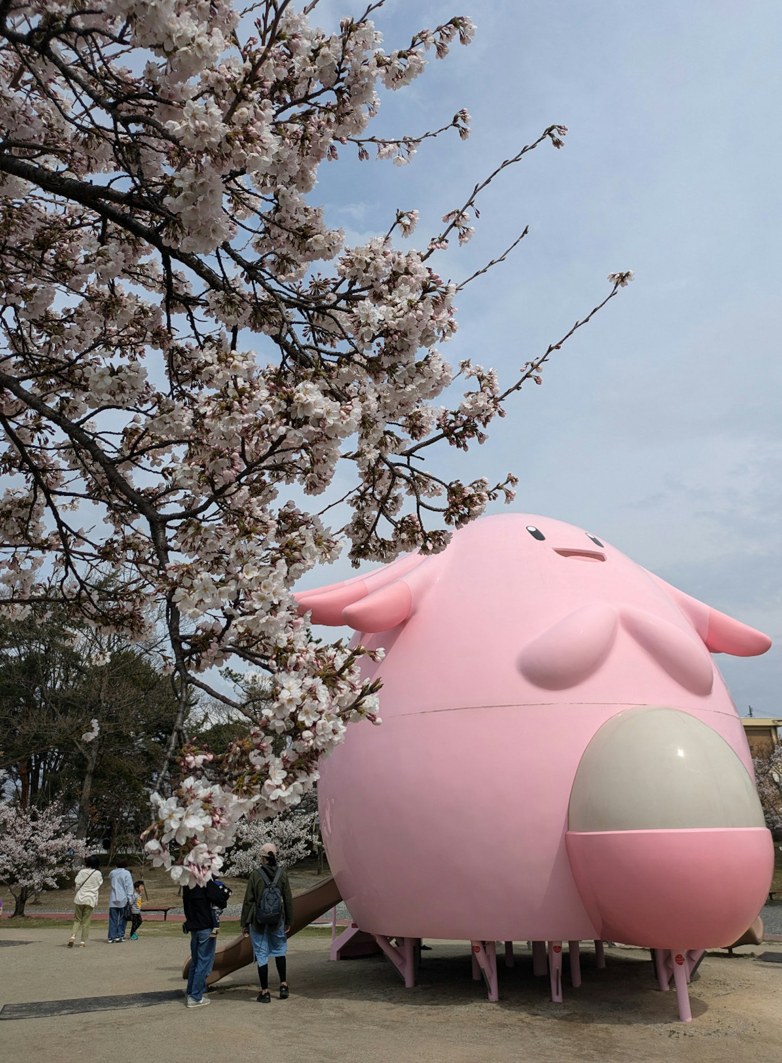 桜の木の下にある大きなピンクのキャラクターのオブジェ
