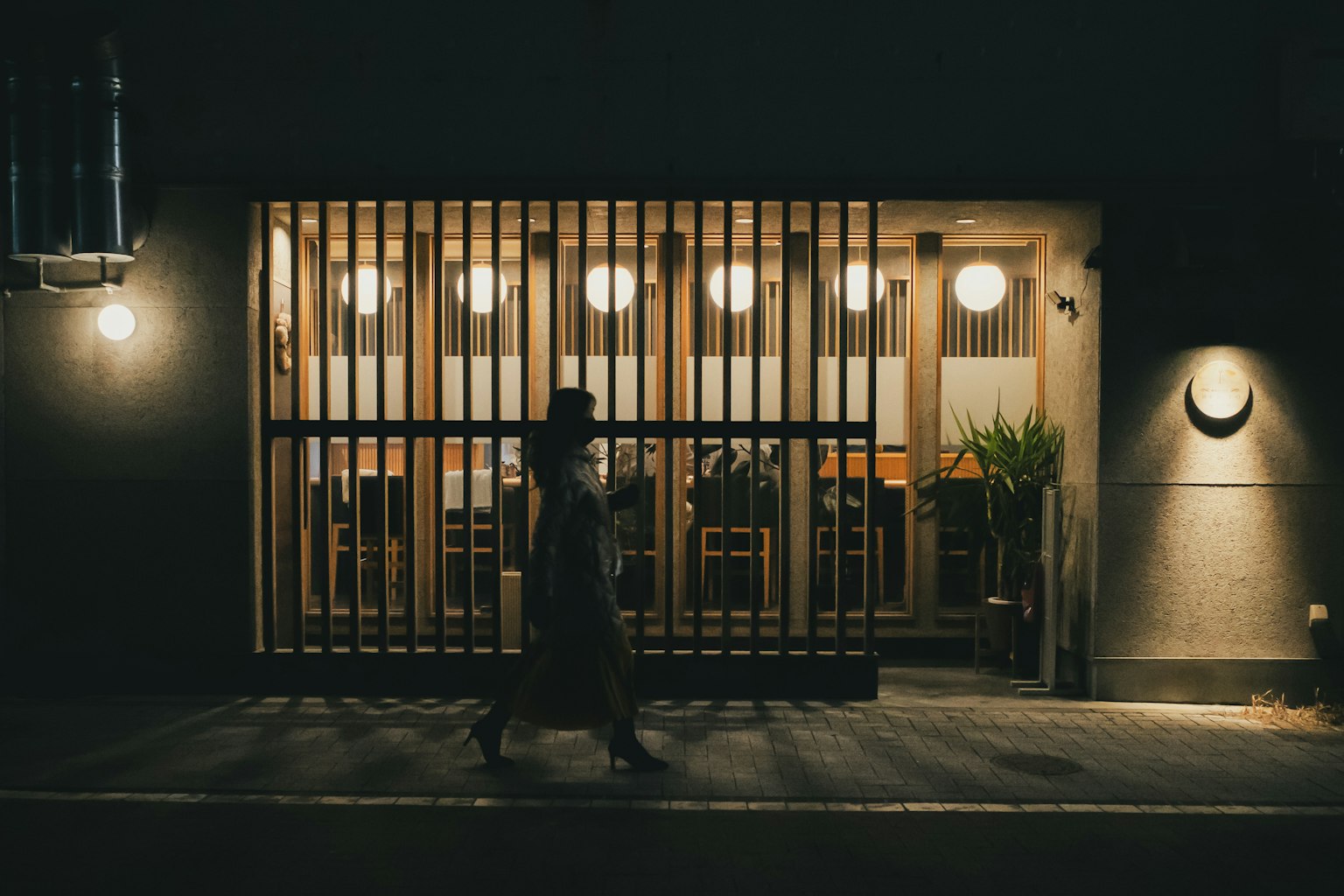 Ngoại thất của nhà hàng Nhật Bản truyền thống vào ban đêm với một người đi qua