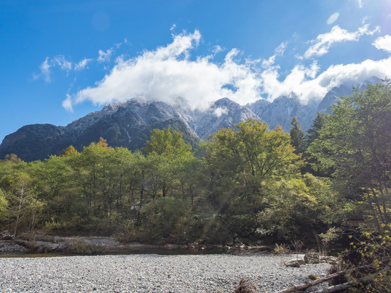 美丽的山脉与云朵和绿色树木在蓝天之下的风景