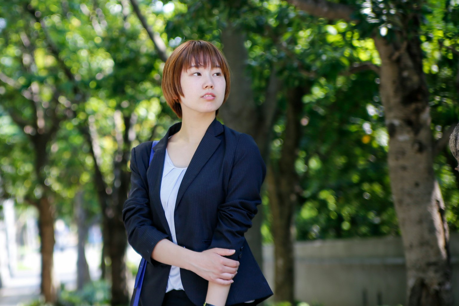 A young woman in a black jacket standing in a park