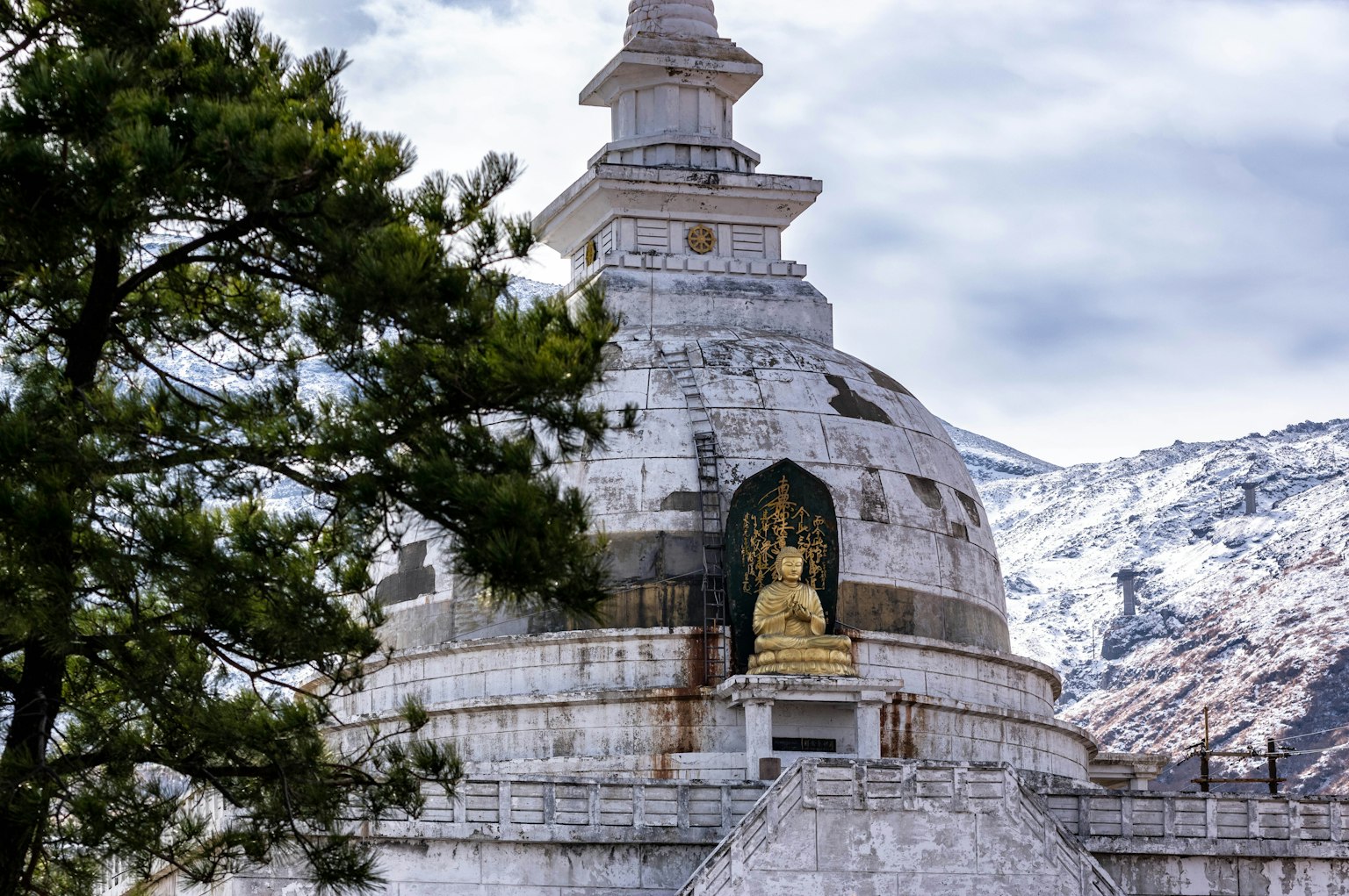 Stupa avec une statue de Bouddha sur fond de montagnes enneigées