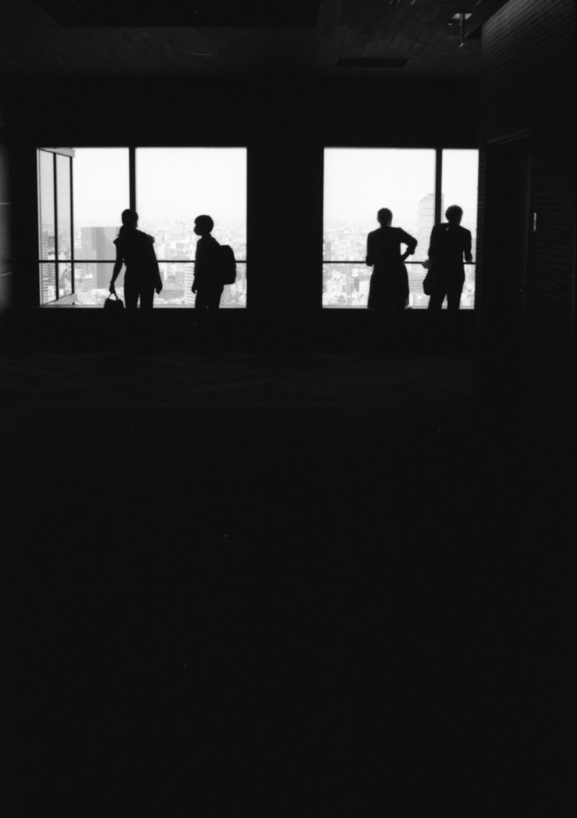 Personensilhouetten im Innenraum vor hellem Fensterlicht