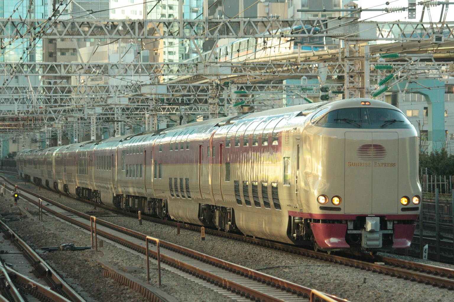 Treno espresso che corre sui binari con uno sfondo urbano di sera