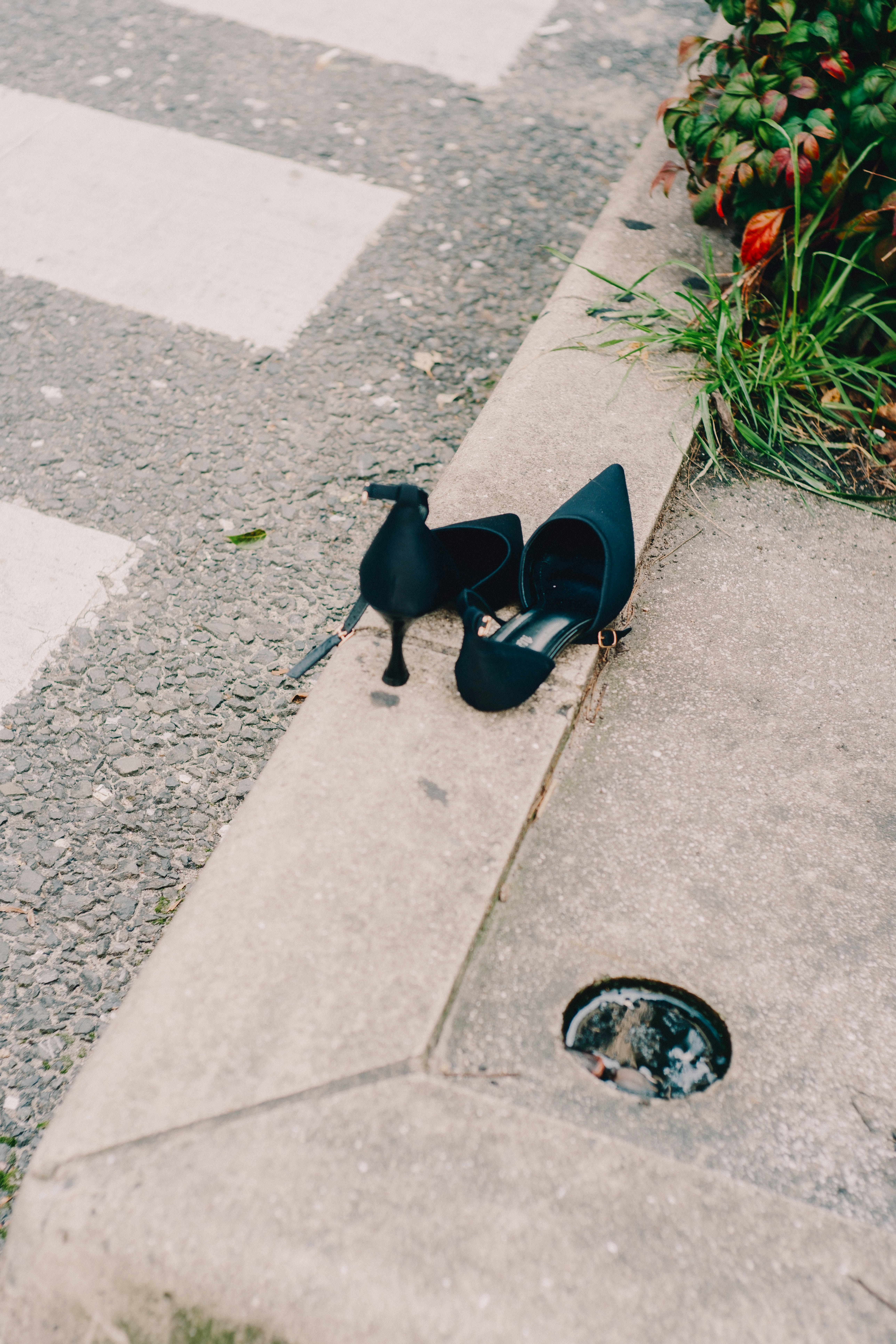 black shoes and a bag placed on a sidewalk curb
