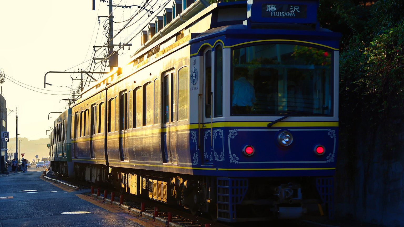 Blue train parked at the station with sunset in the background