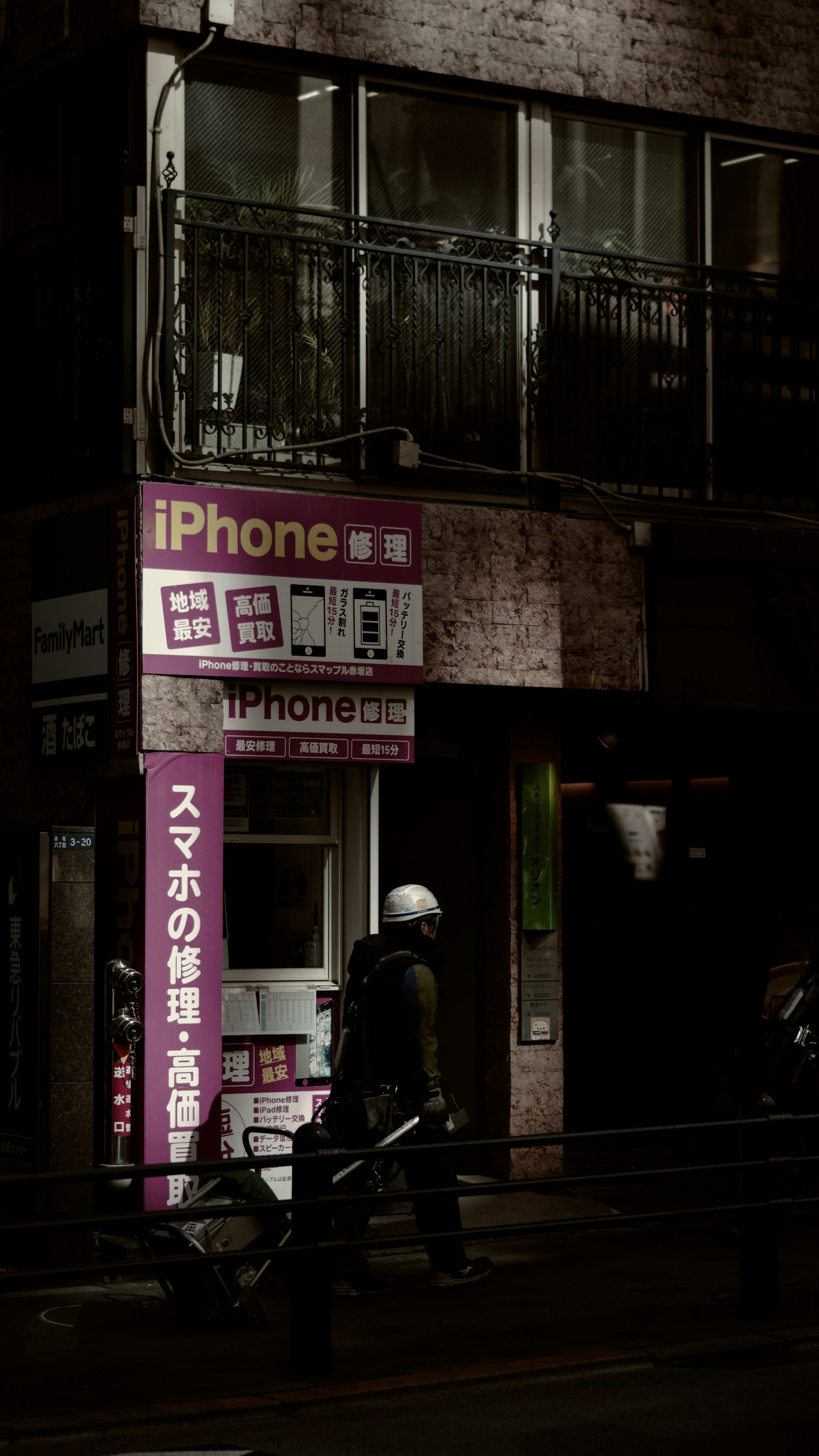 Panneau de réparation d'iPhone dans une rue sombre avec une personne au travail