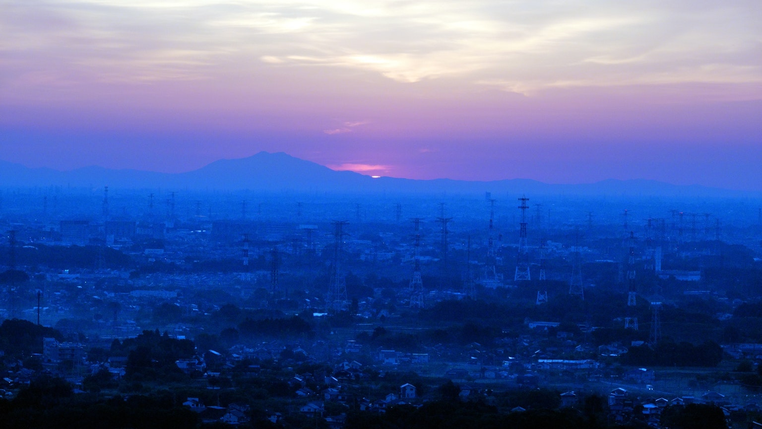 ท้องฟ้ายามเย็นสีน้ำเงินเหนือทิวทัศน์เมืองพร้อมพระอาทิตย์ตก