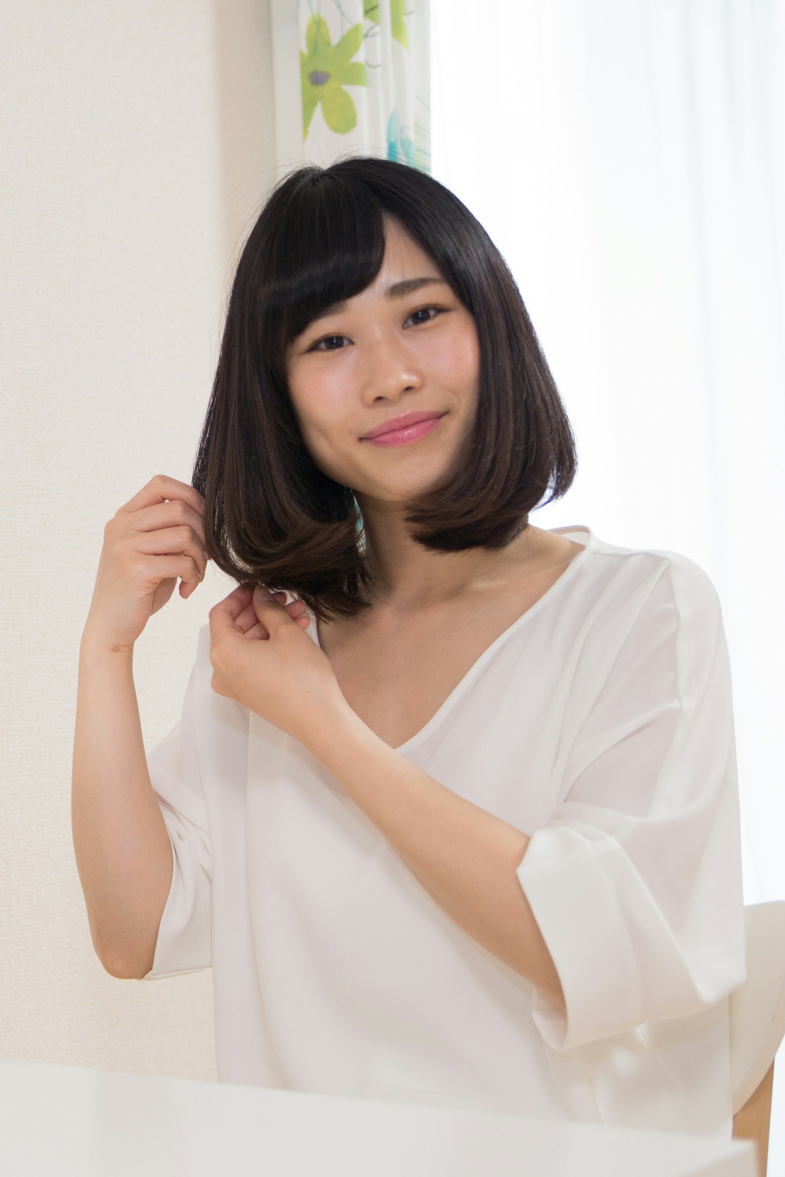 Woman in a white top adjusting her hair
