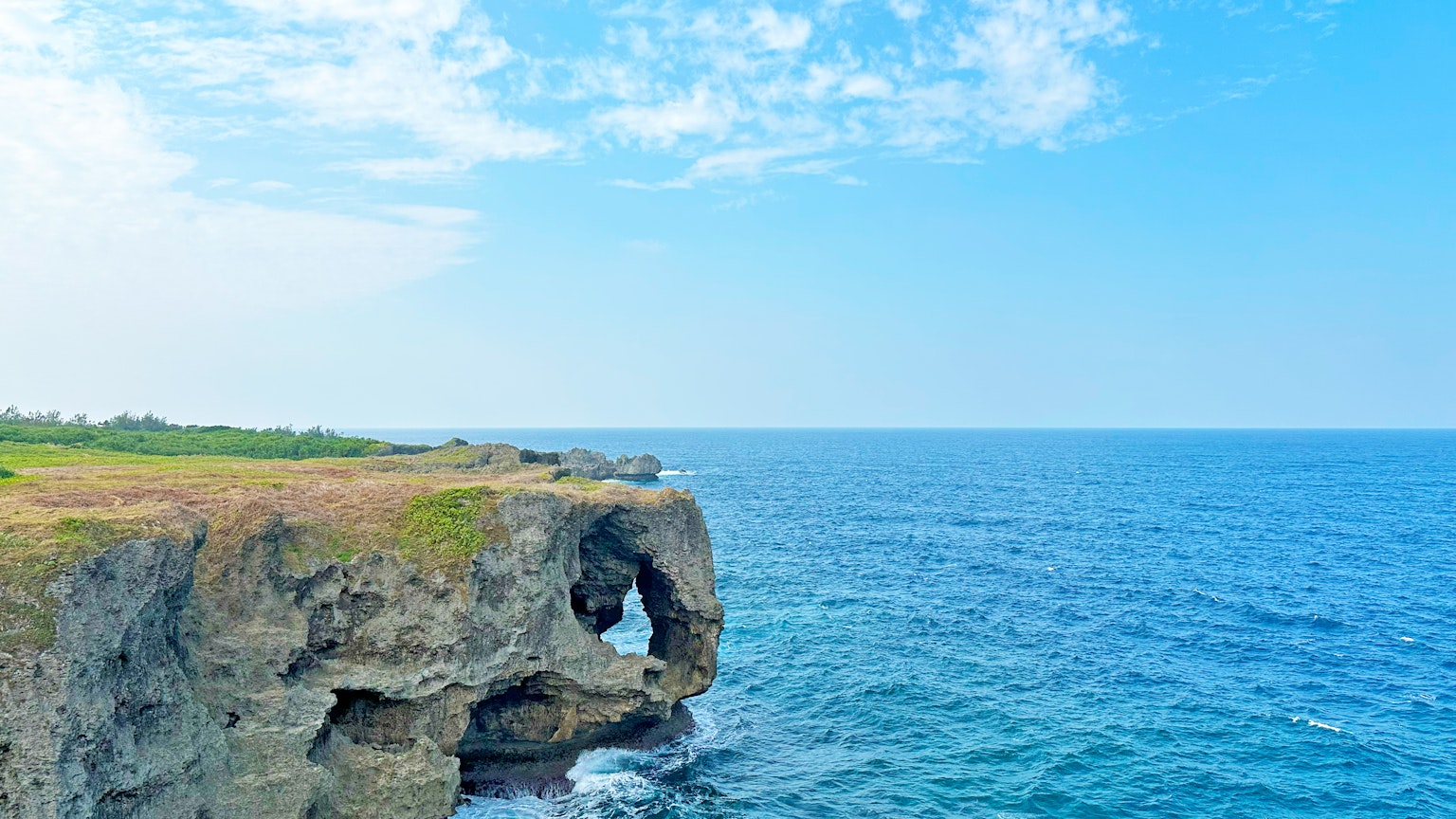 Hermoso paisaje de mar y cielo azul con acantilados rocosos y hierba verde