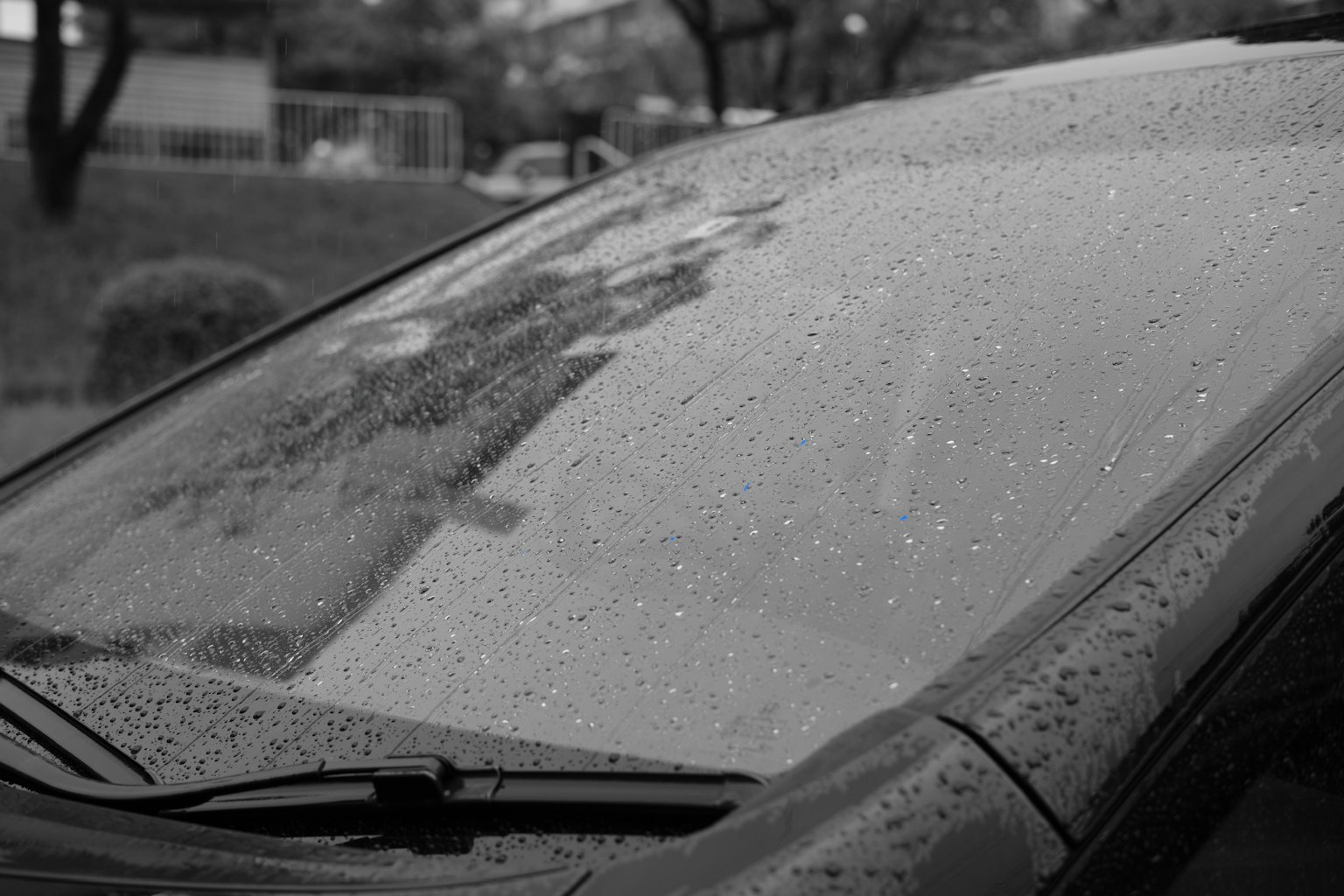 Gros plan sur le pare-brise d'une voiture noire avec des gouttes de pluie