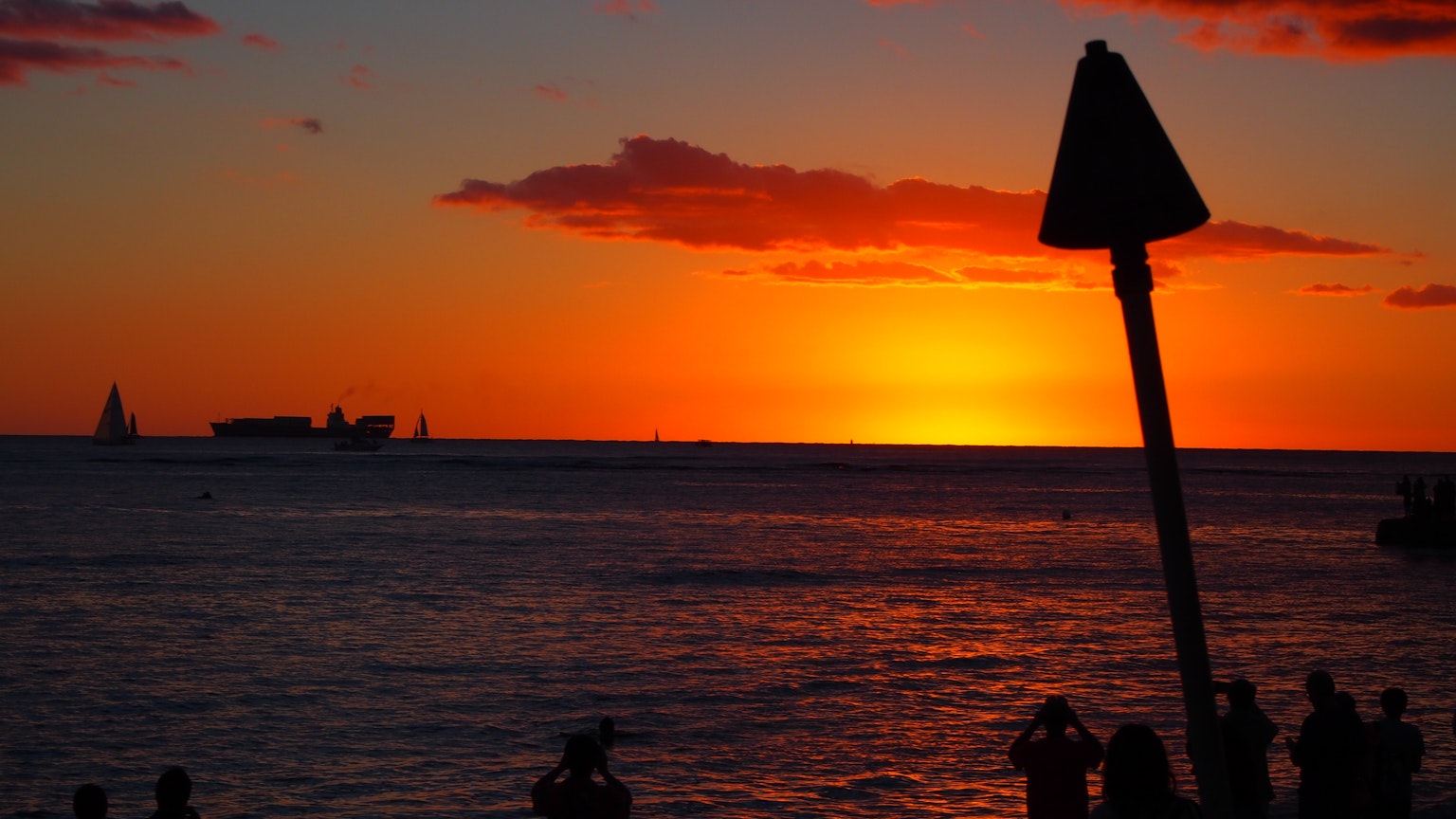 Silhouette di persone che guardano il tramonto sull'oceano