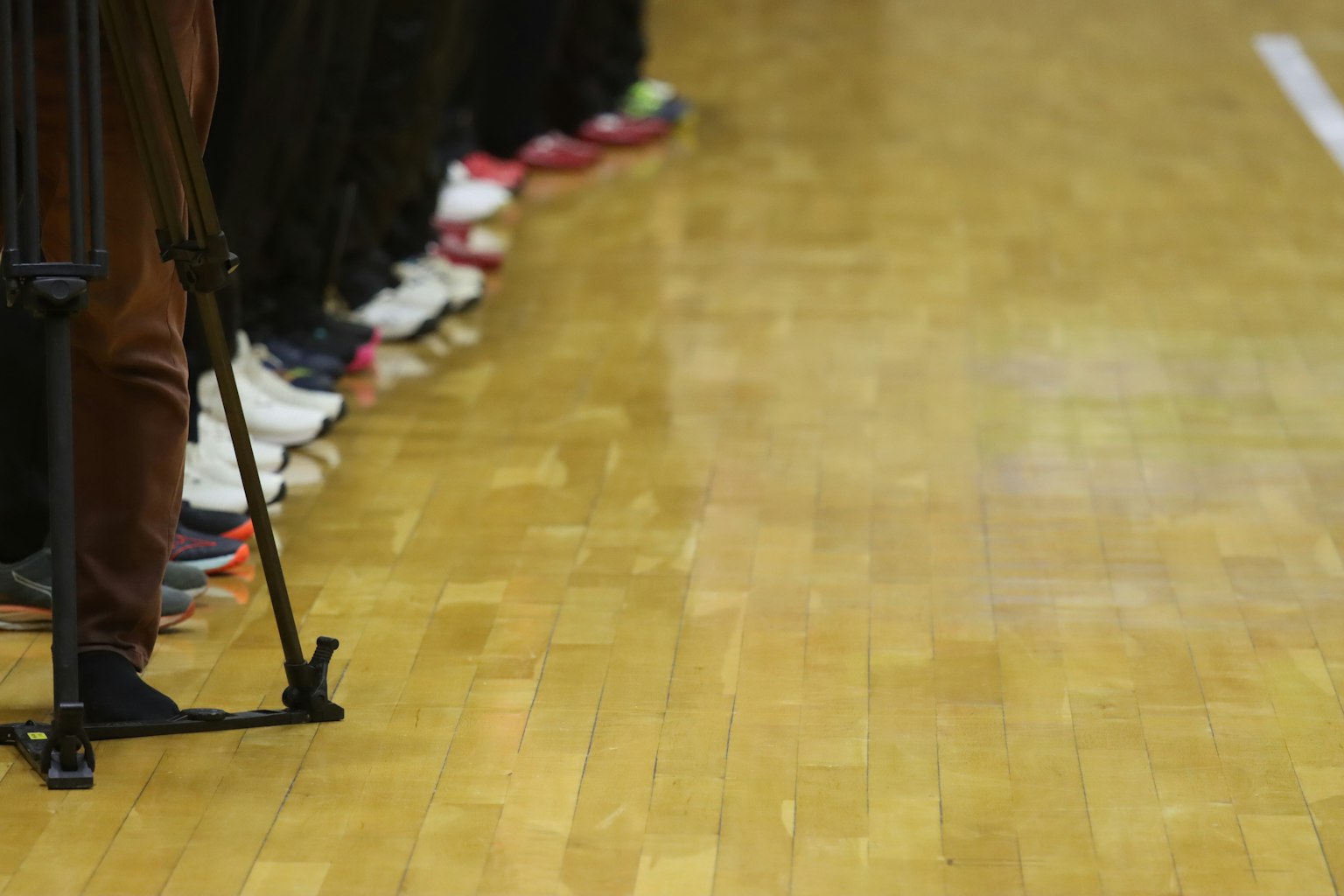 Fila de zapatillas a lo largo de una cancha de baloncesto con un trípode de cámara