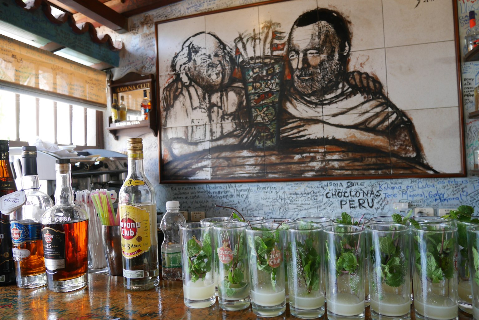 Bar-Theke mit Cocktailgläsern und einem Wandgemälde von zwei Figuren