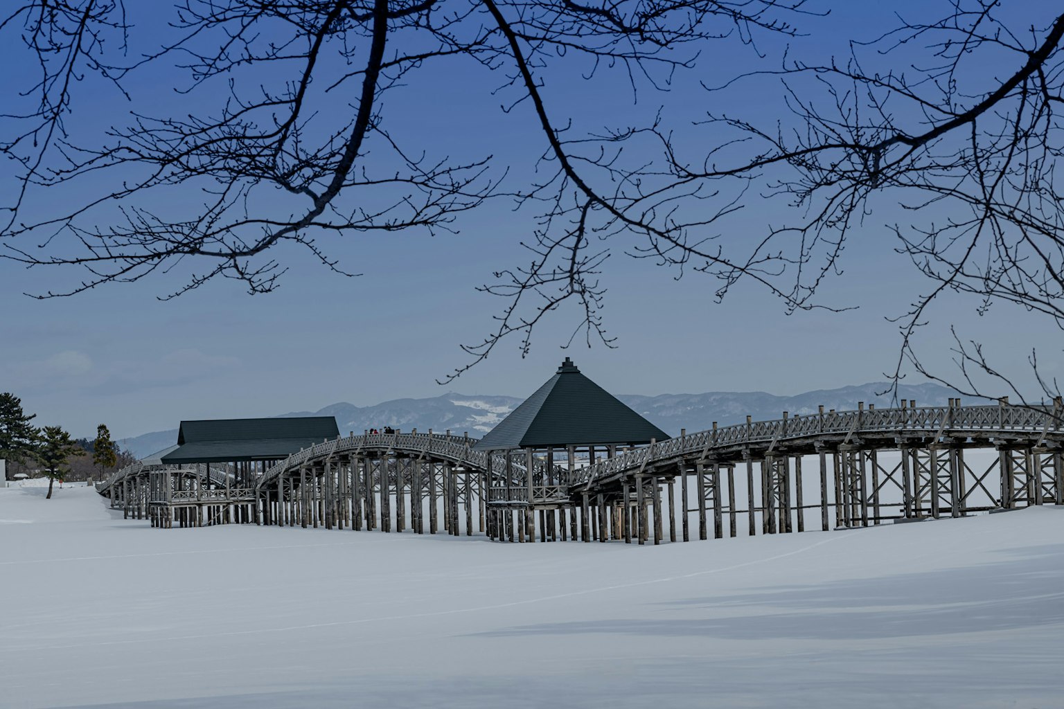 雪覆盖的景观中的木桥和小屋