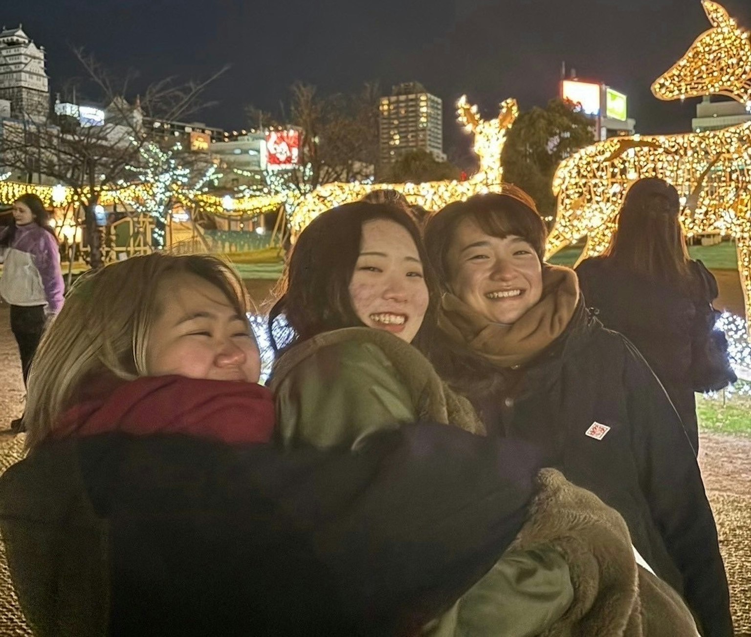 밤에 빛나는 축제 조명 아래에서 웃고 있는 세 여성