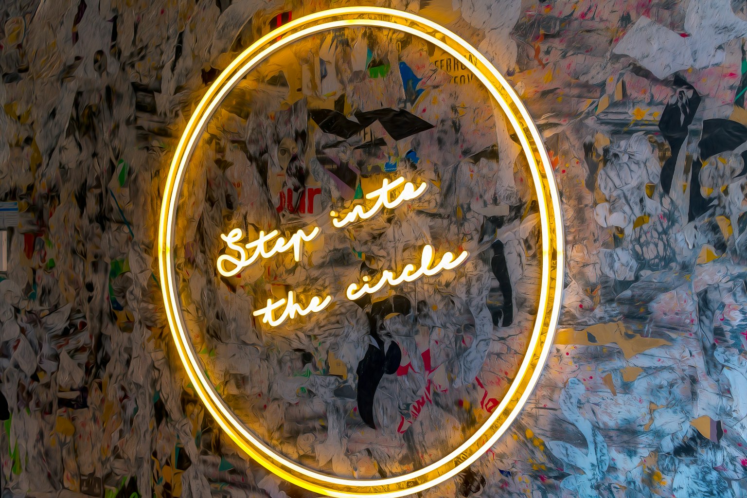 Cartel de neón en forma circular que dice Step into the circle en una pared texturizada