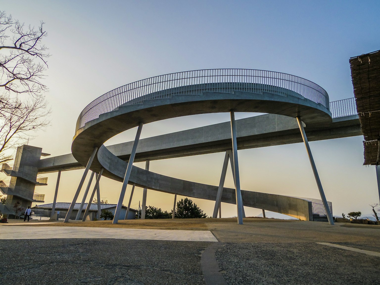 Ponte pedonale a spirale moderna contro un tramonto