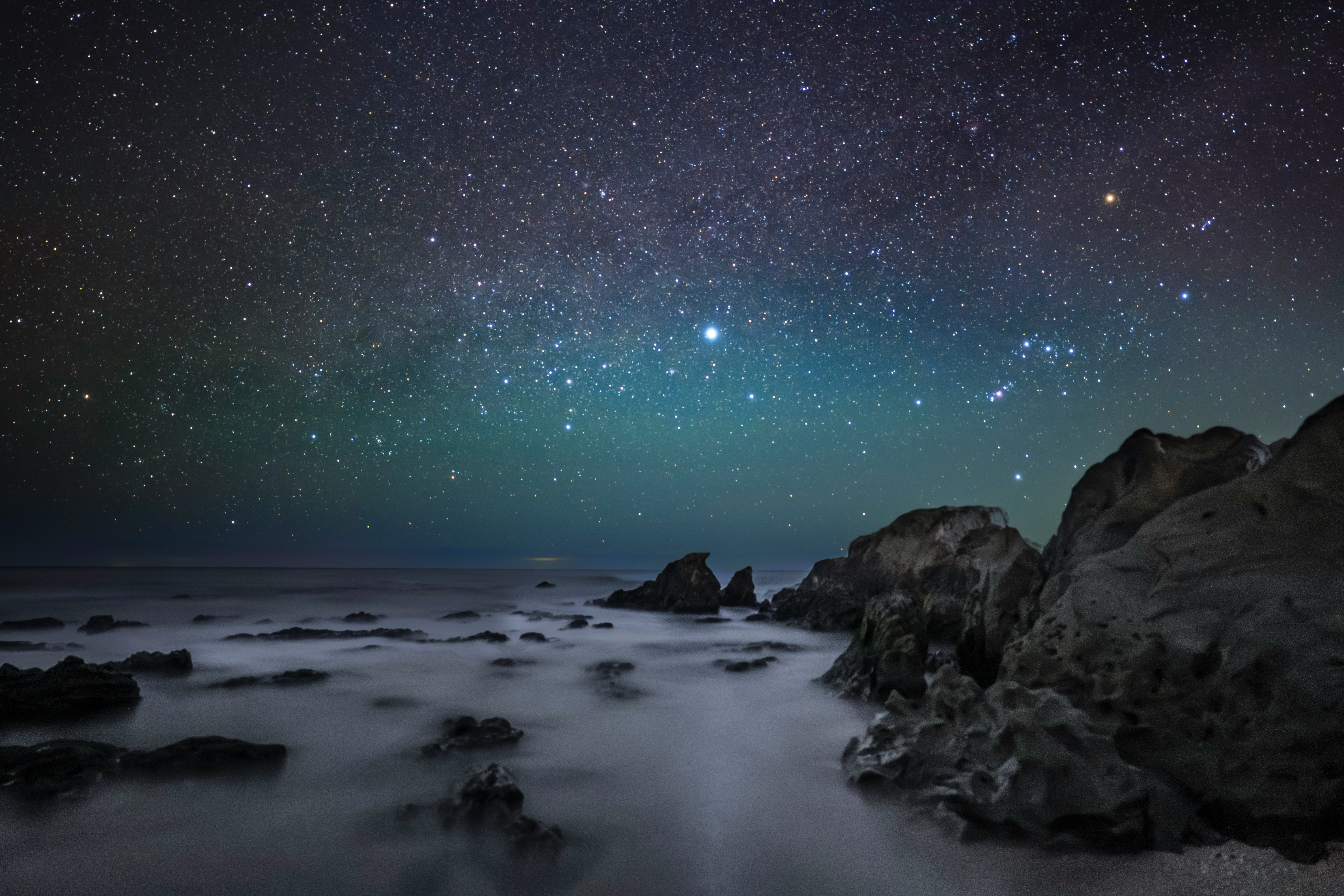 星空の下の海岸と岩場の波しぶき