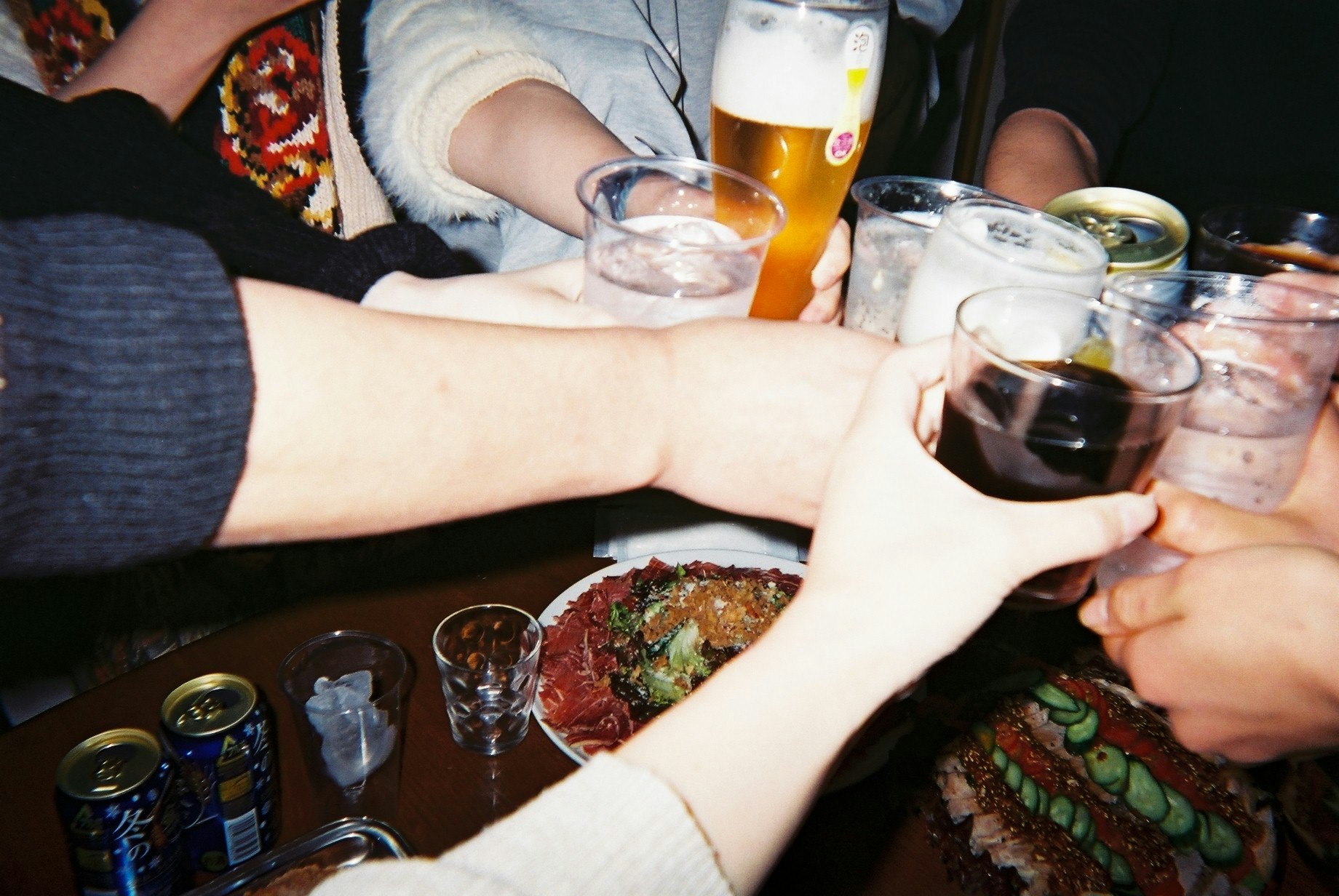 友人たちの乾杯と手に持ったビール・グラスの食卓