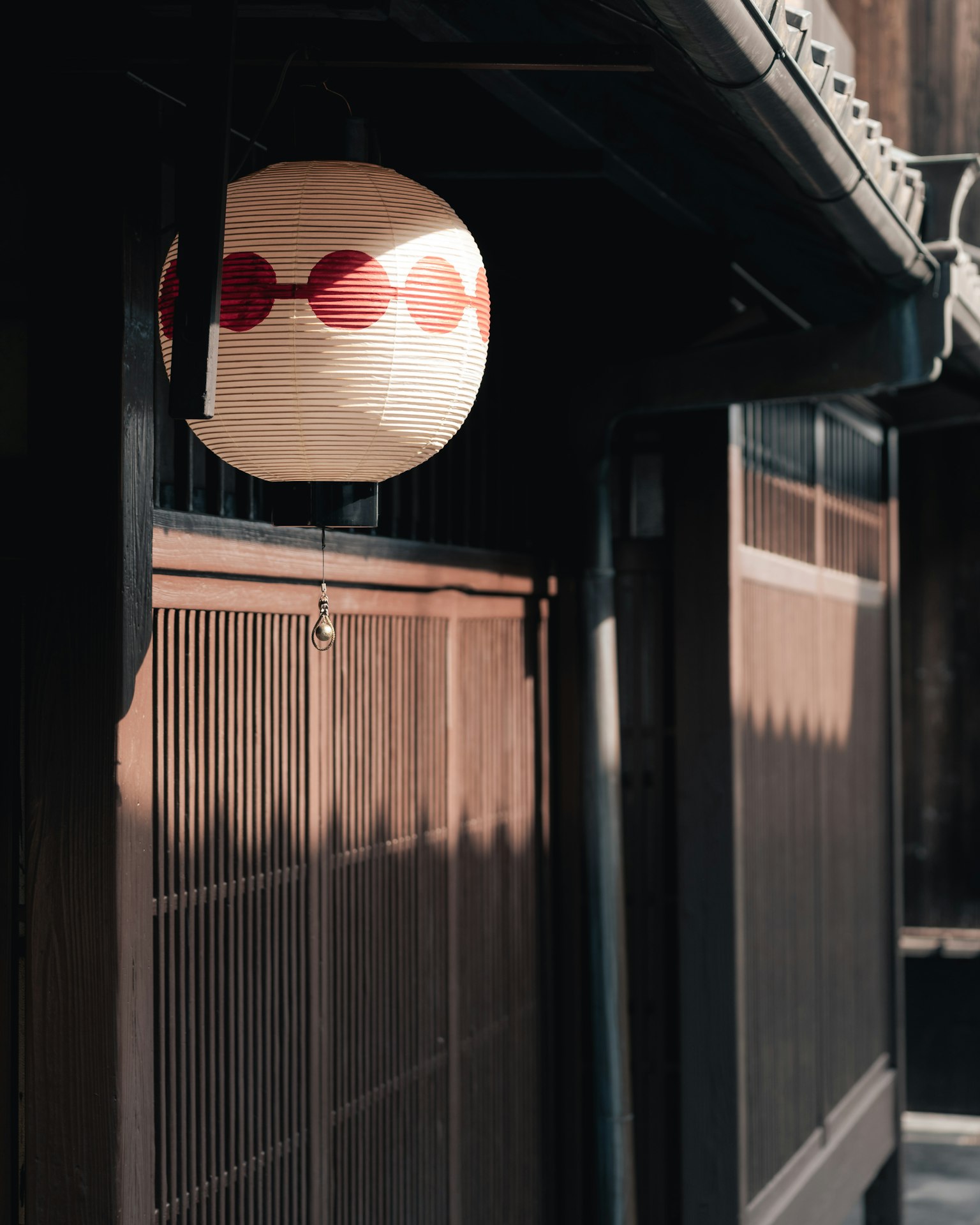 傳統日本燈籠，紅色圖案，懸掛在一座老舊木屋前