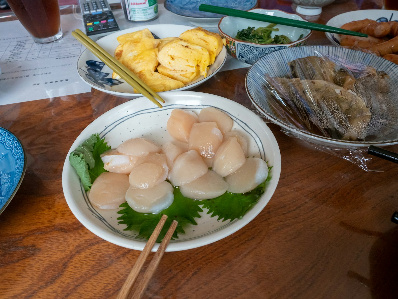 Sashimi de vieira fresca dispuesto en un plato con platos circundantes