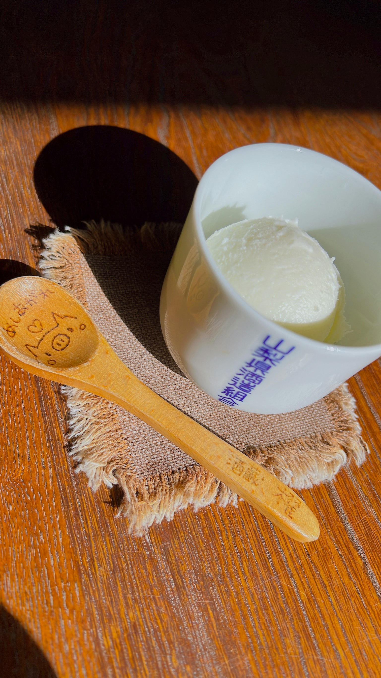 Una tazza di gelato bianco con un cucchiaio di legno su un tavolo