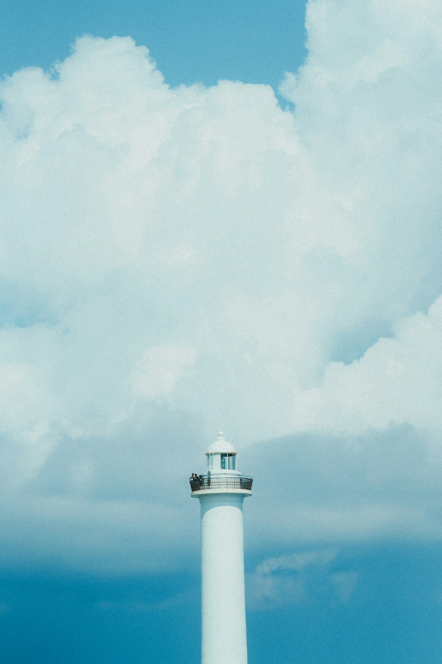 Immagine di un faro contro un cielo blu e nuvole bianche
