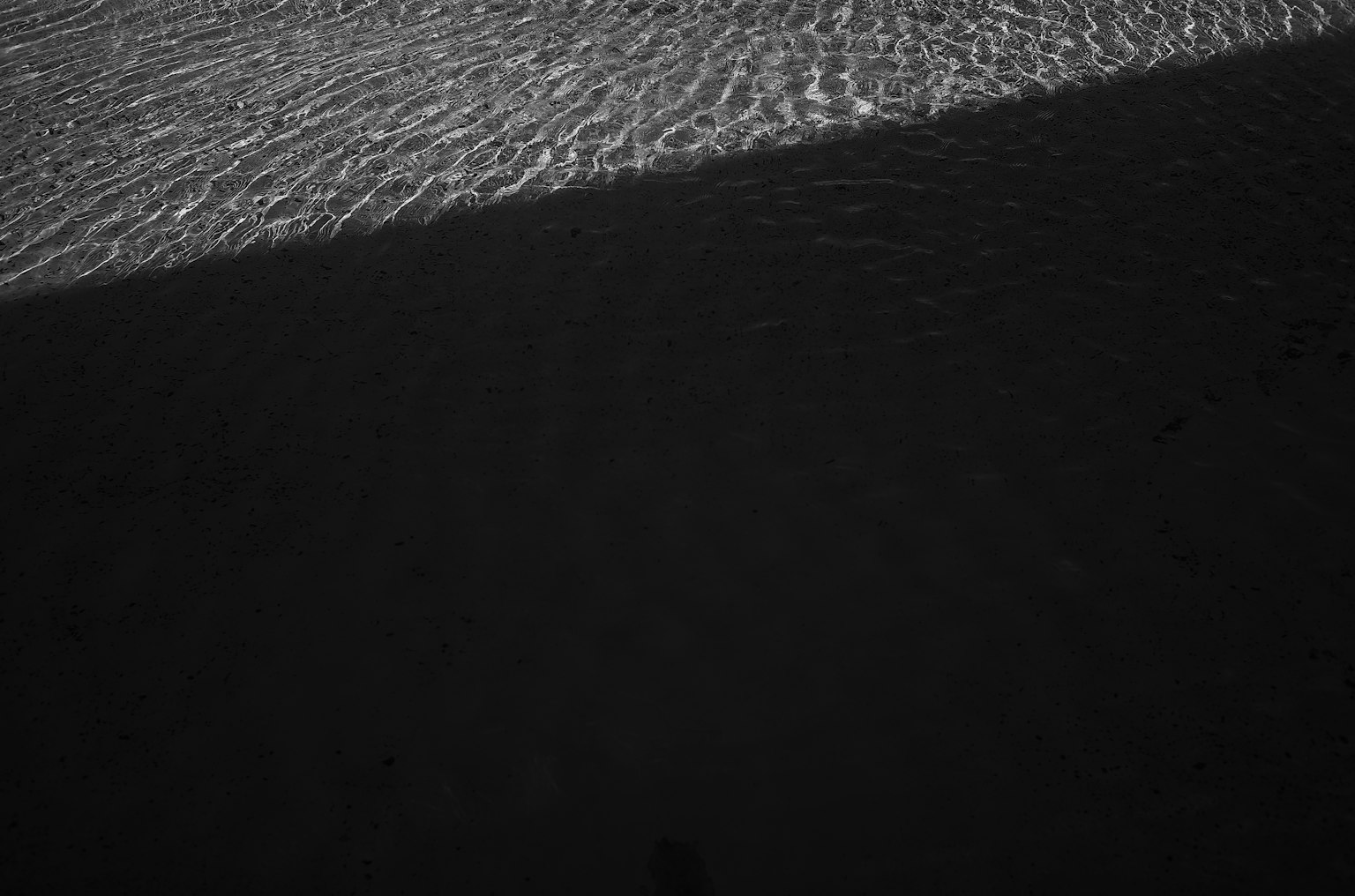 Immagine in bianco e nero che cattura il contrasto tra le ondulazioni dell'acqua e l'ombra