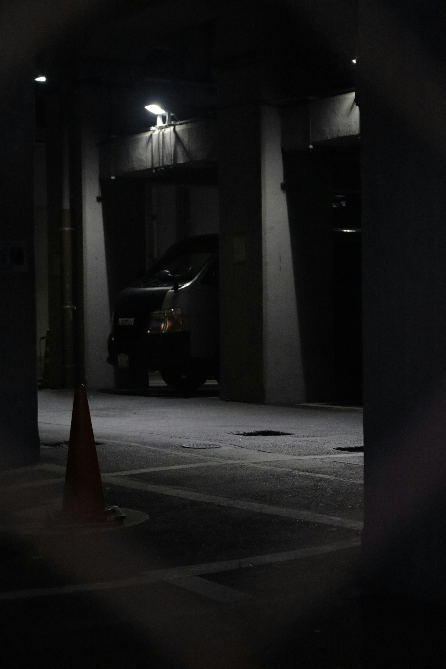 어두운 주차장에 주차된 차량과 주황색 원뿔