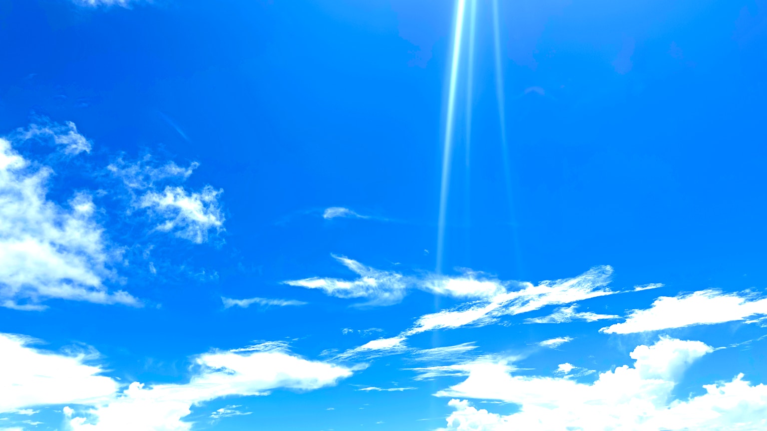 Ciel bleu vif avec des nuages blancs et des rayons de soleil