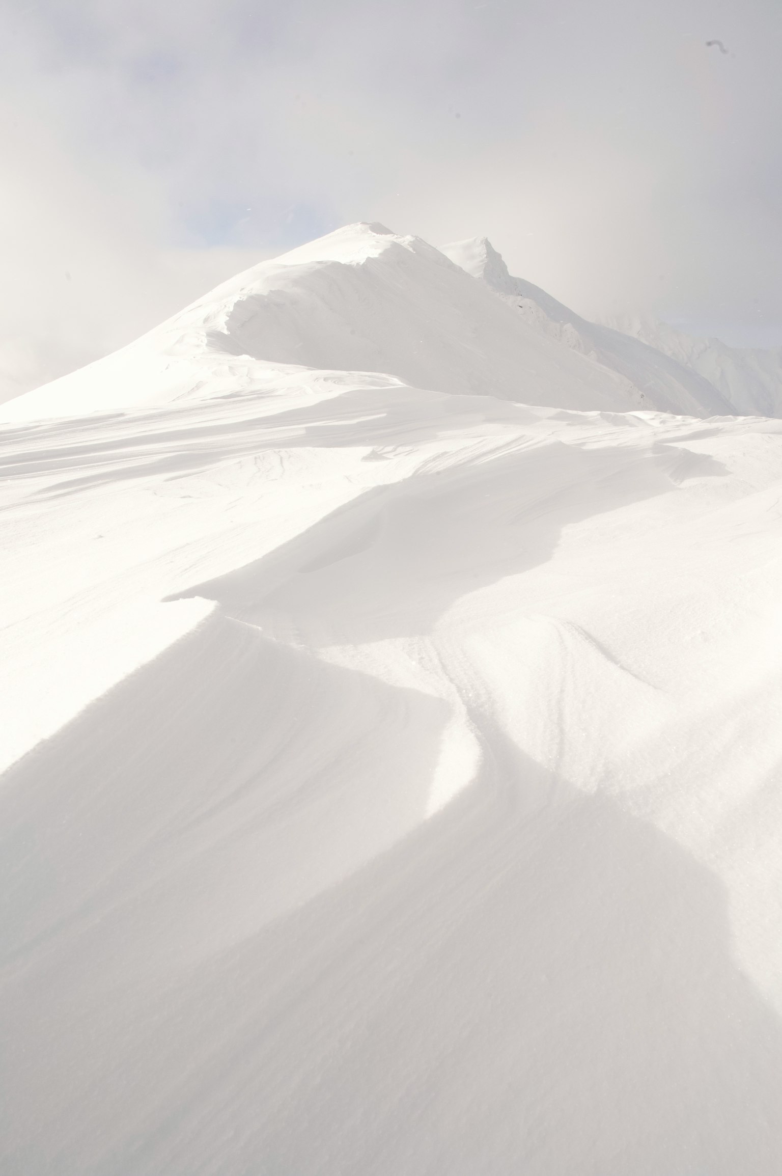 Snow-covered mountain slope with soft curves and shadows