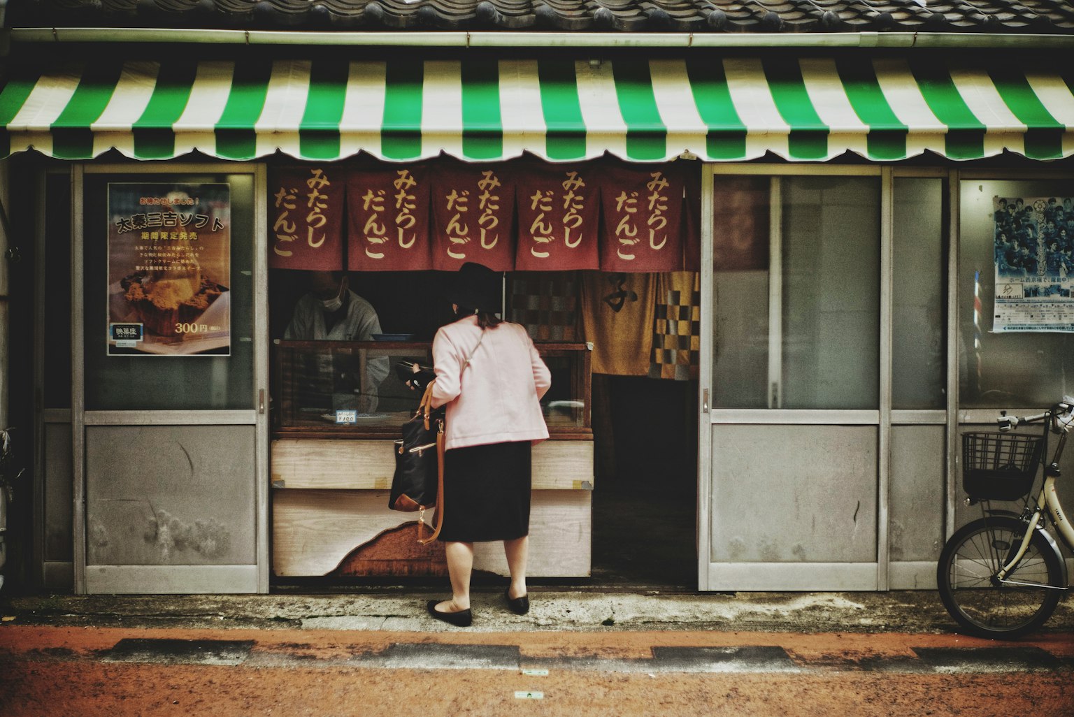 여성이 줄무늬 차양 아래 작은 가게에서 음식을 주문하고 있다