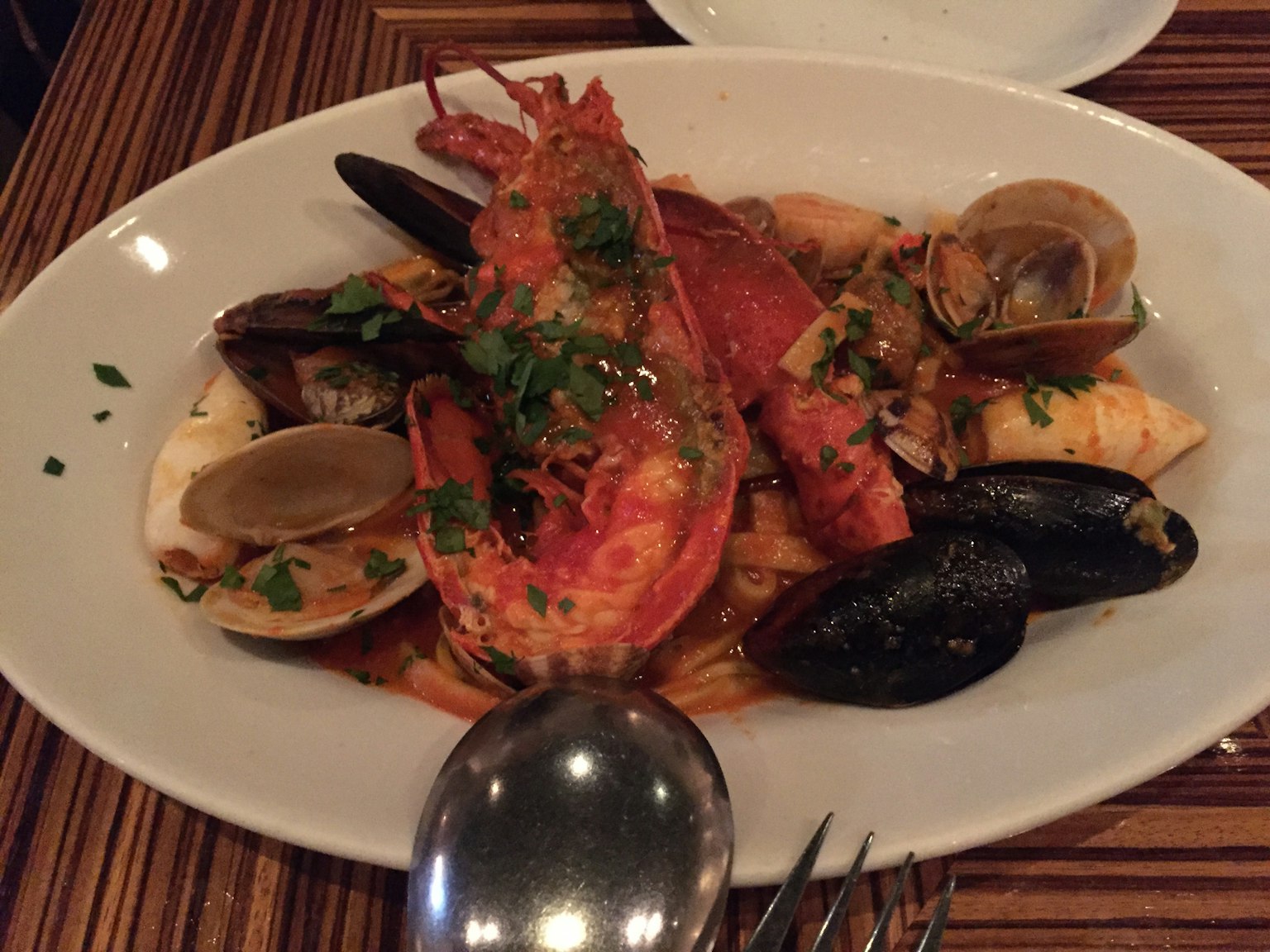 Un plato de mariscos con langosta, almejas y mejillones decorado con perejil