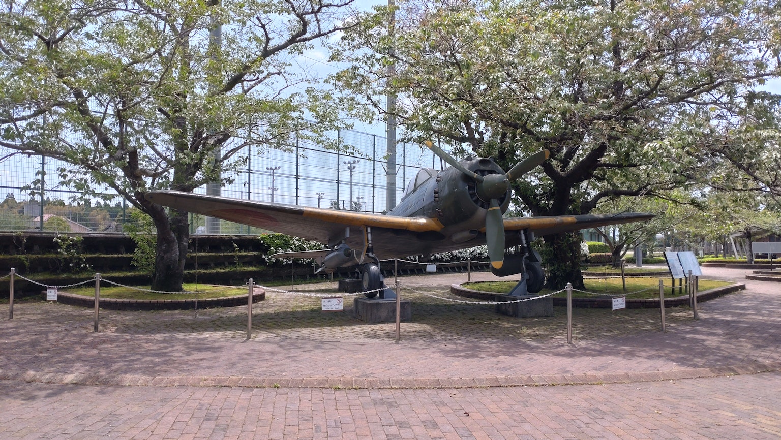 Un aereo da combattimento esposto in un parco circondato da alberi rigogliosi