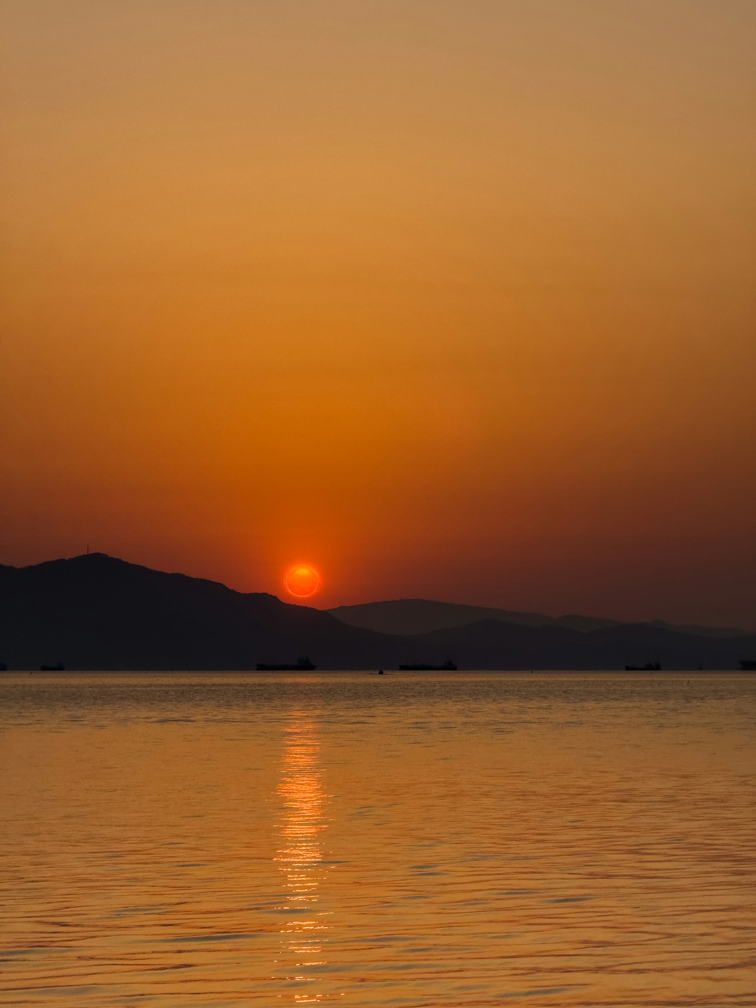 Pemandangan matahari terbenam yang indah di atas laut dengan siluet pegunungan