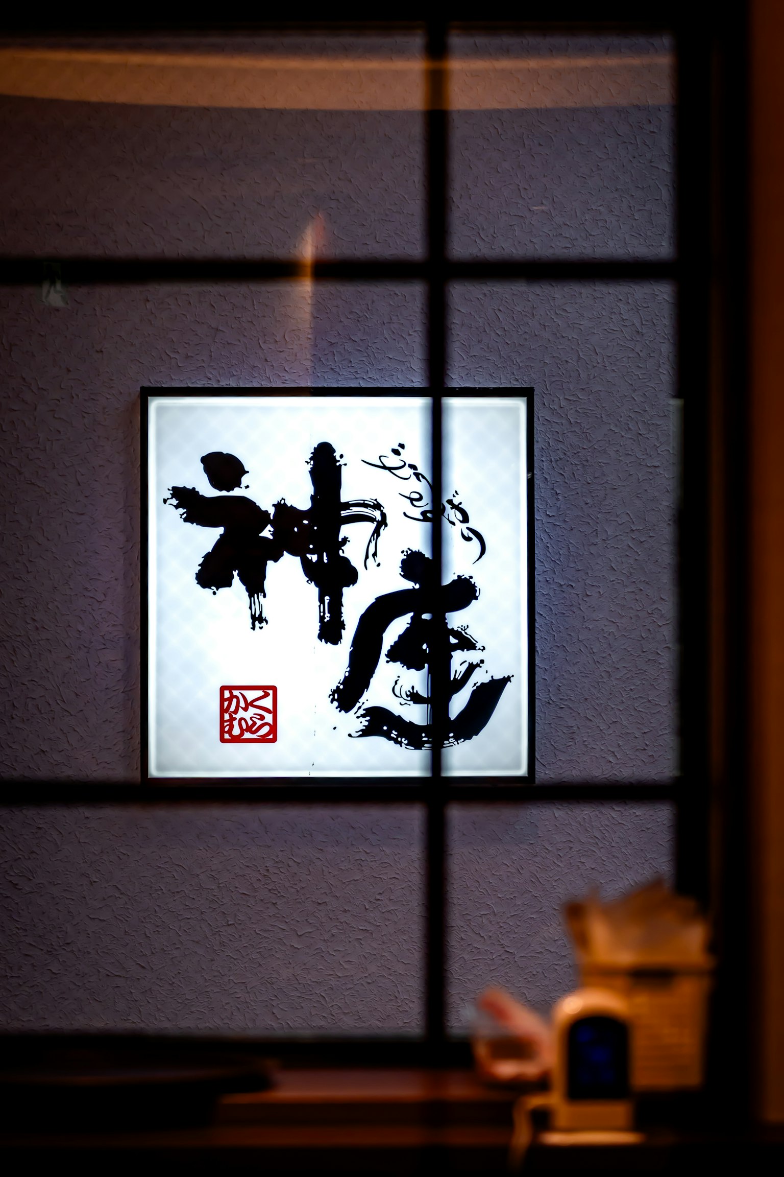 一幅白色框架的艺术作品，上面有黑色书法，挂在墙上