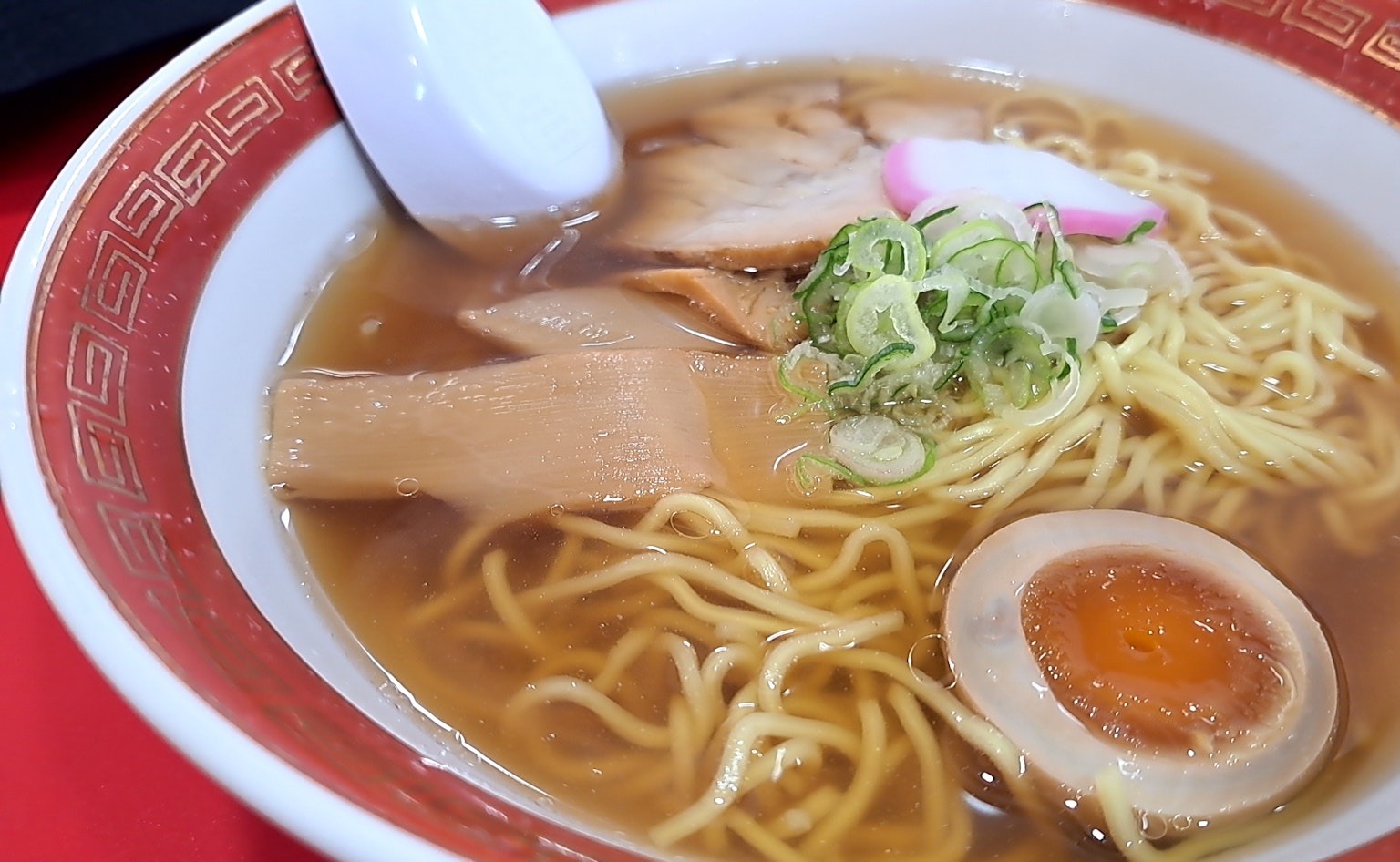 Eine Schüssel Ramen mit Brühe Nudeln Scheiben Schweinefleisch Frühlingszwiebeln und einem weichgekochten Ei