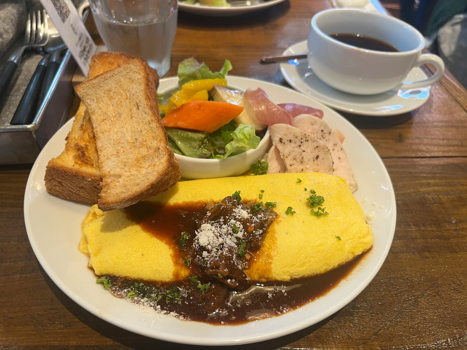 Plato de desayuno con omelette, ensalada, tostadas y café
