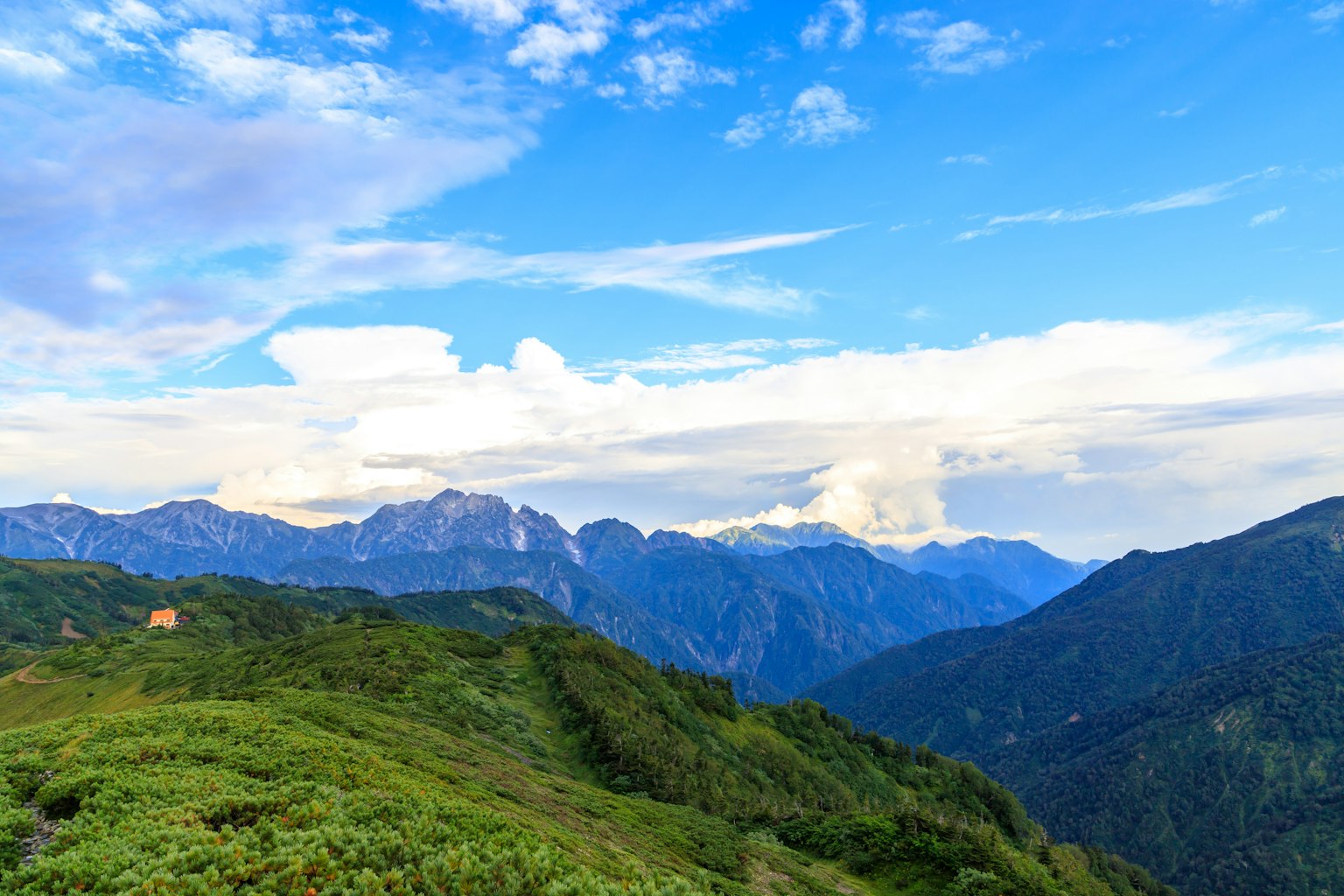 蓝天和云下的山脉风景郁郁葱葱的绿色山丘和遥远的山峰