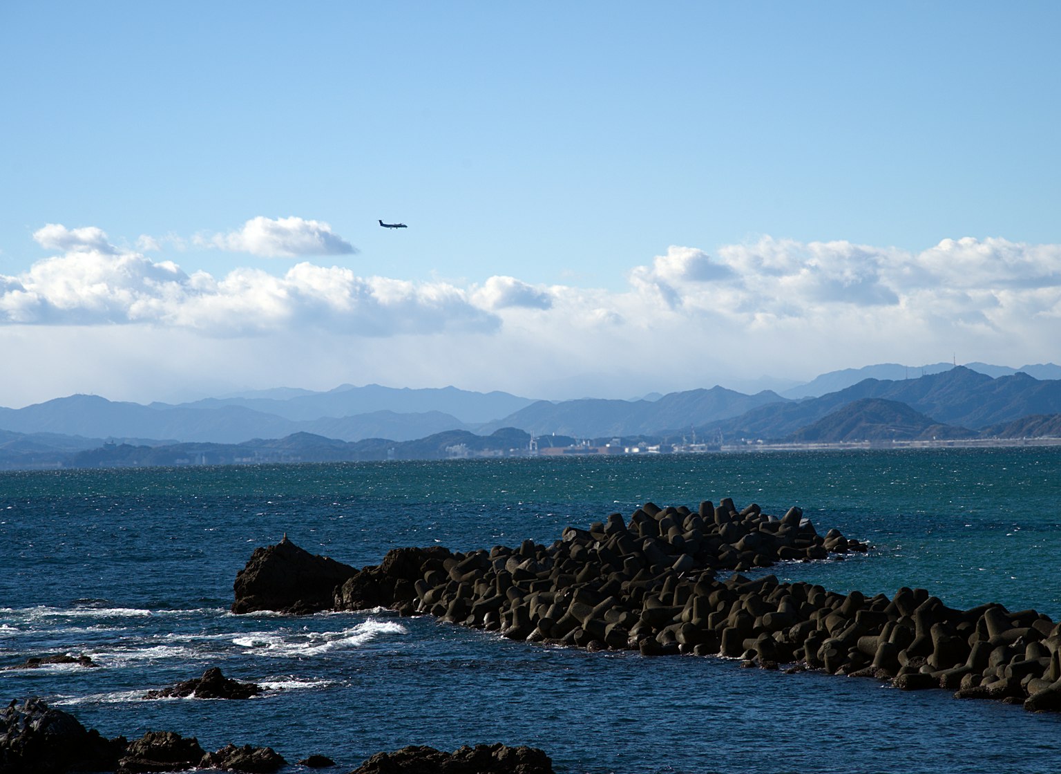 蓝色海洋与岩石海岸和天空中的飞机
