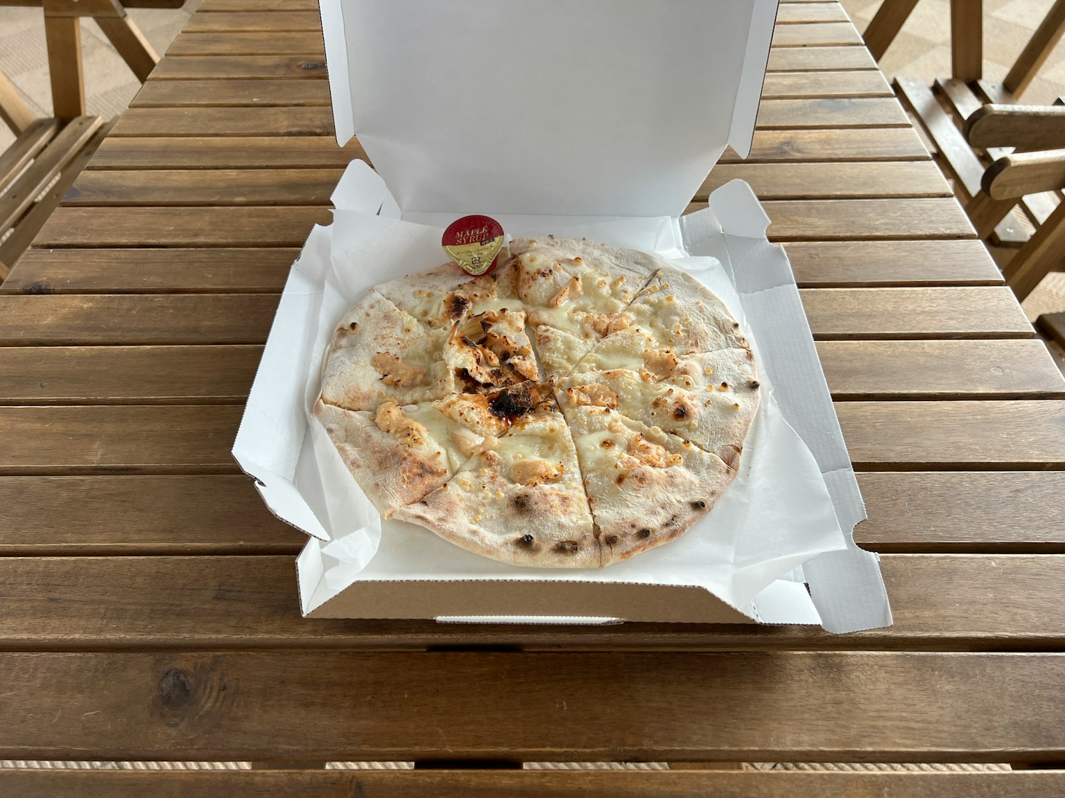 Pizza dans une boîte blanche sur une table en bois