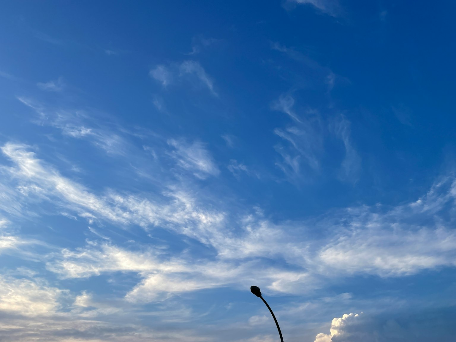 Cielo azul con nubes blancas y silueta de farola