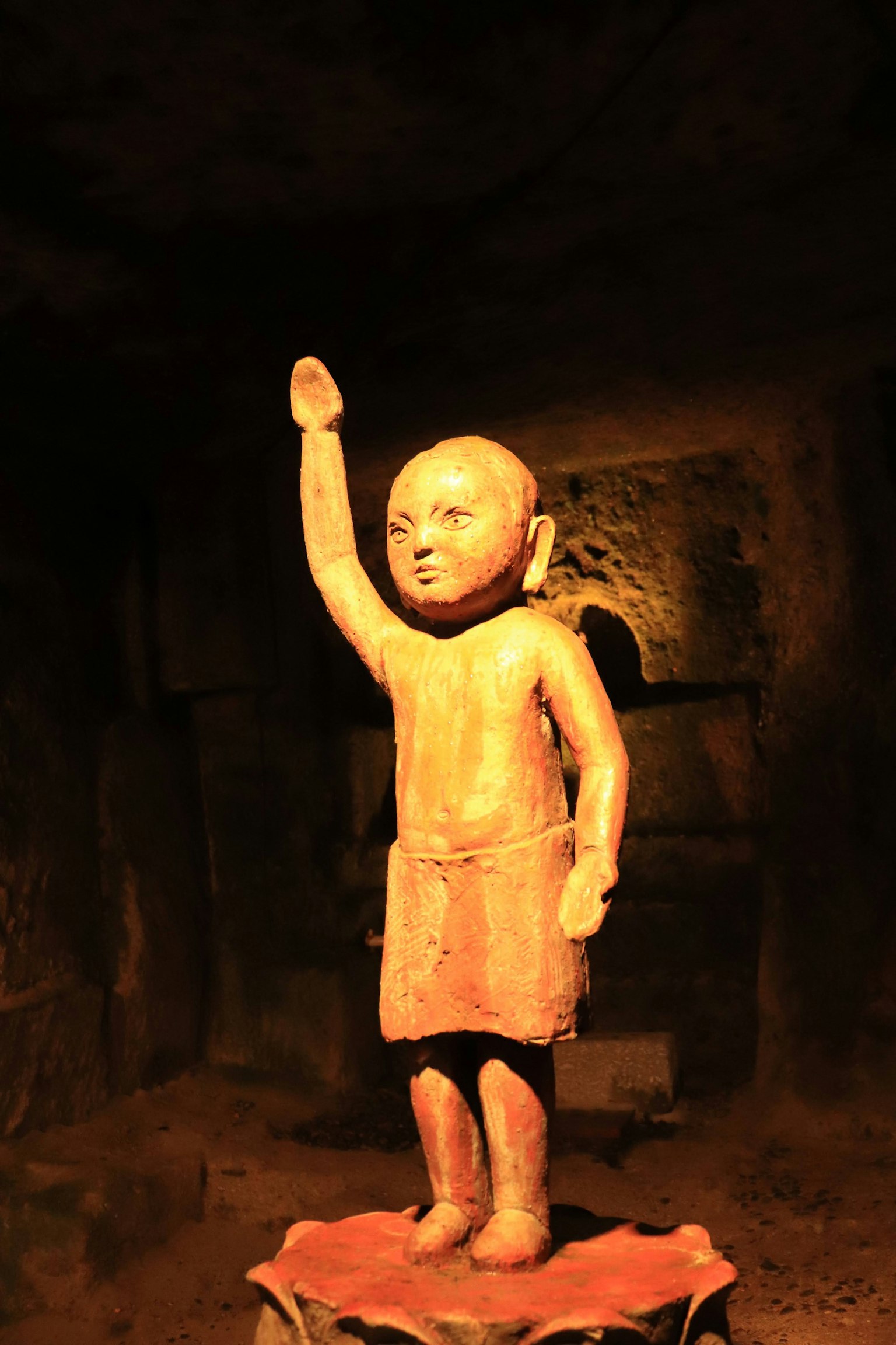 Statue ancienne d'un enfant levant une main