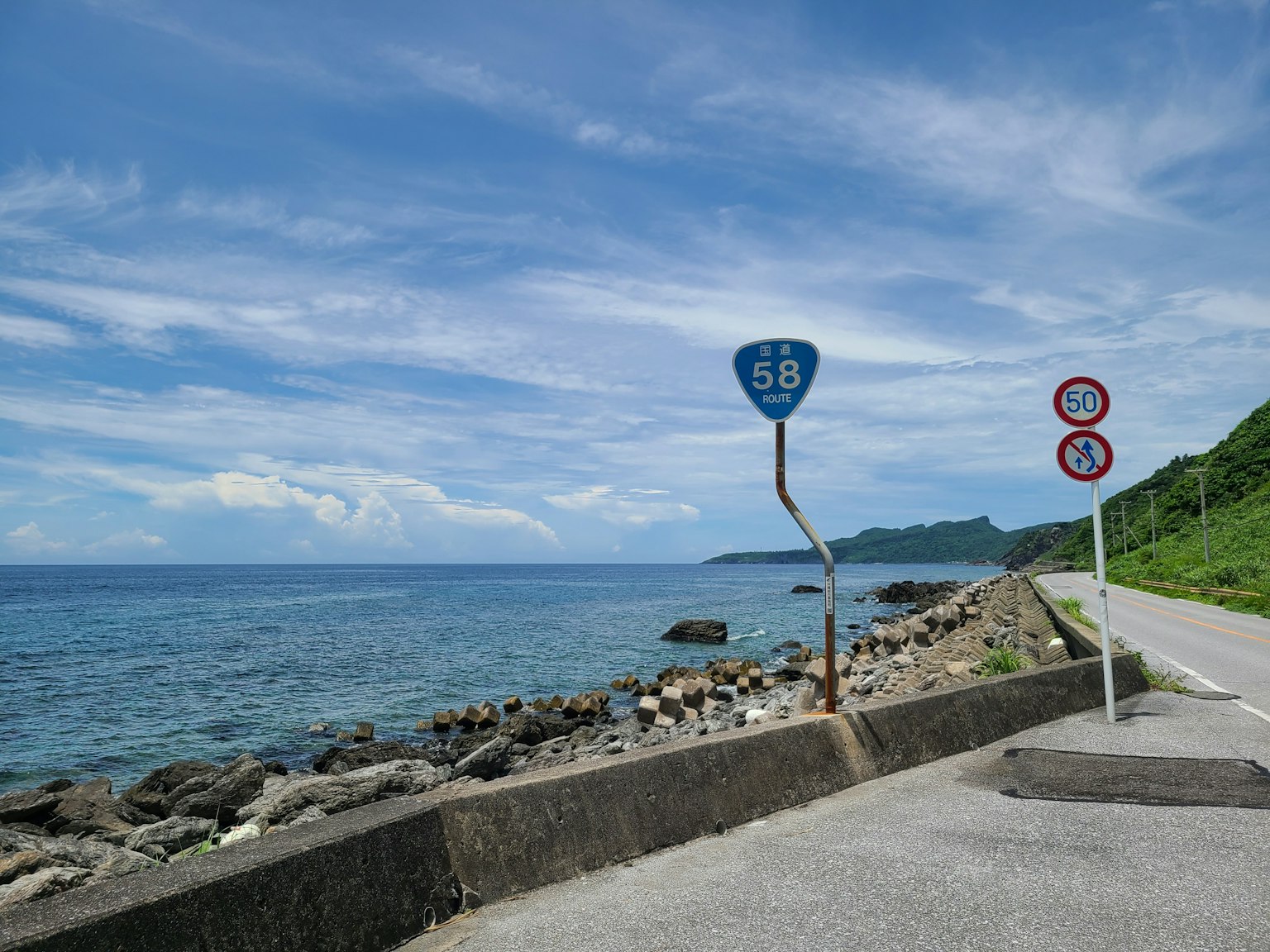 海岸公路与蓝天和海洋景观，包含交通标志和岩石