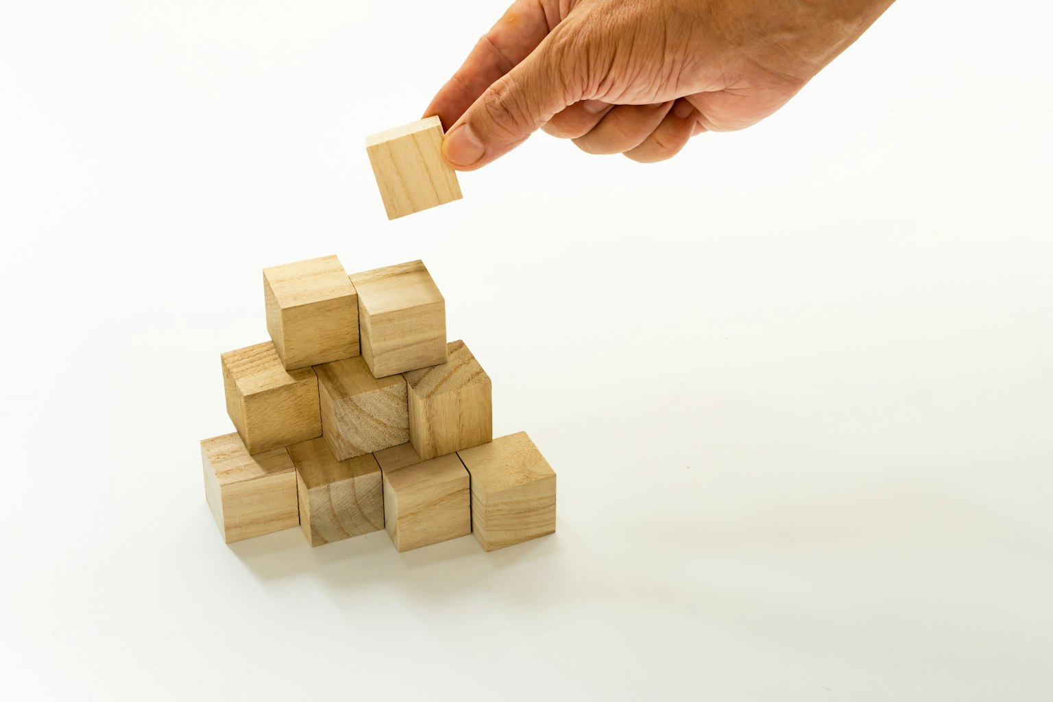 Une main plaçant un bloc en bois sur une pile de blocs