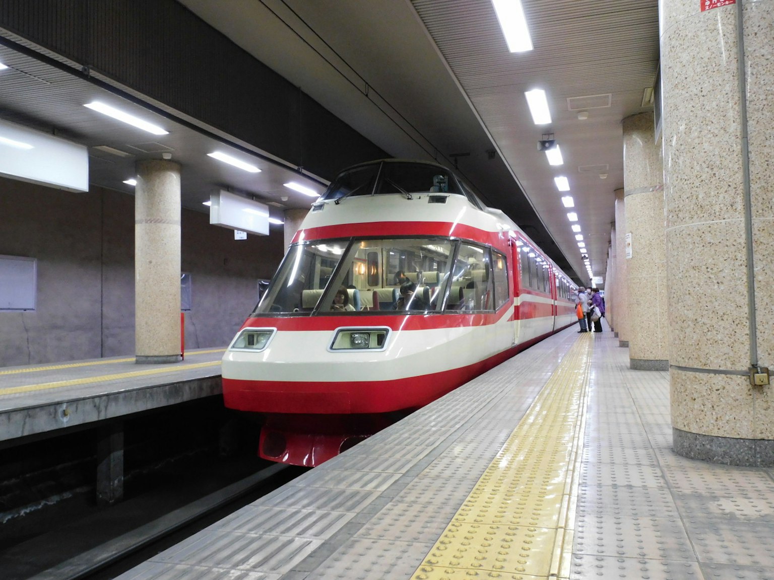 一列帶紅色條紋的火車停在車站月台上