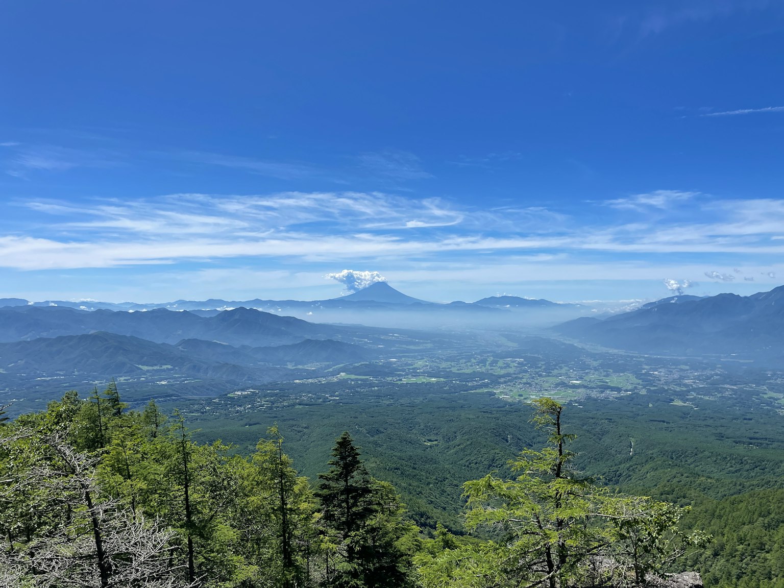 Üppige grüne Berge unter einem blauen Himmel mit einem entfernten Vulkan