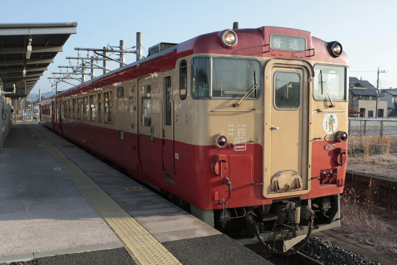 Kereta merah dan krim diparkir di stasiun